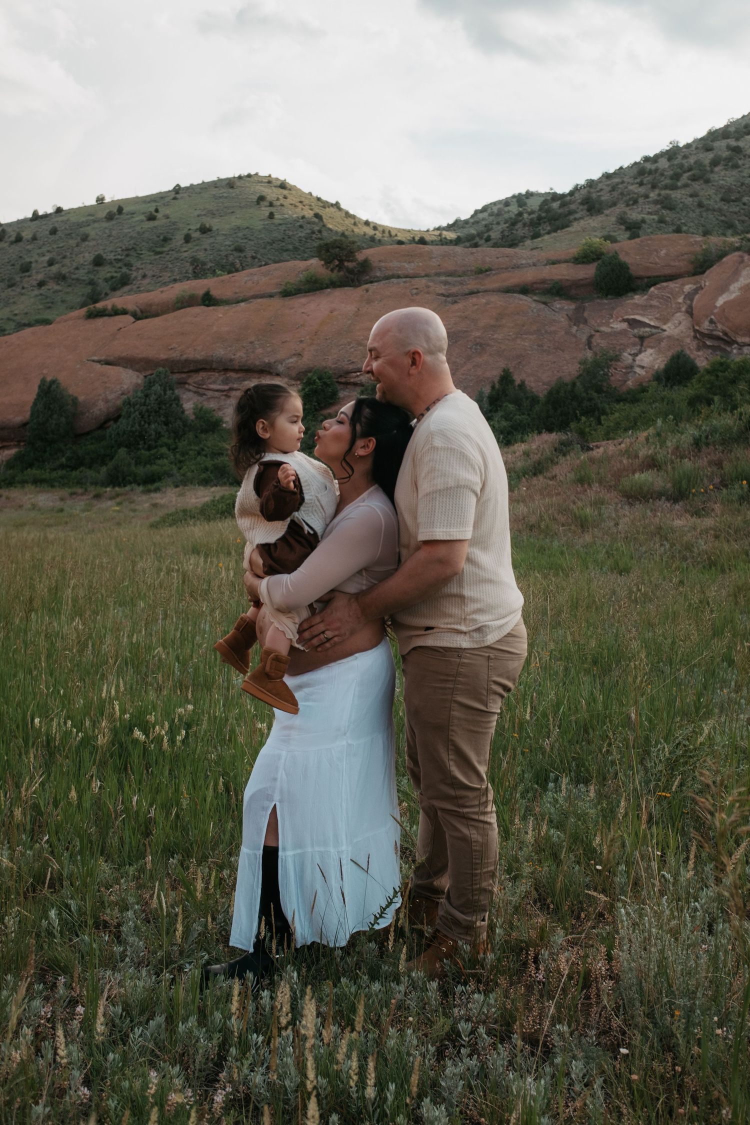 A tender family moment captured against the backdrop of rolling hills and red rocks.