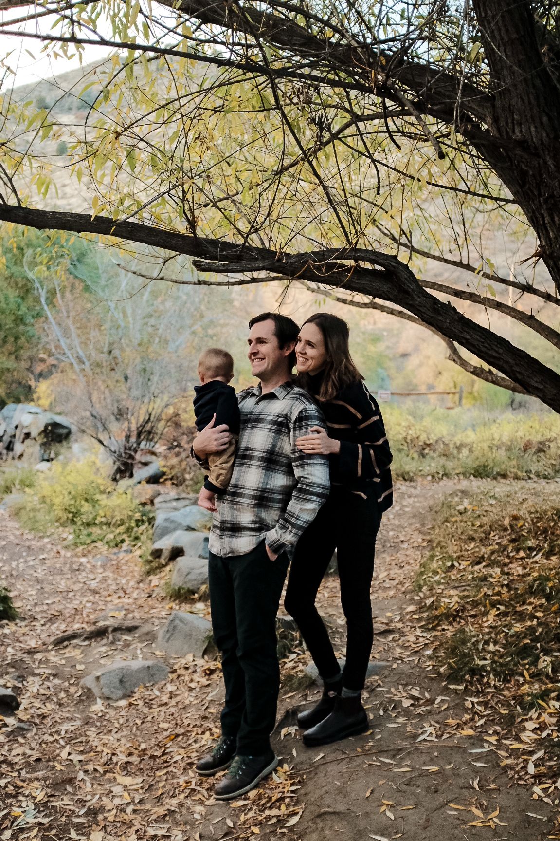 Family shares tender moments together under autumn trees.