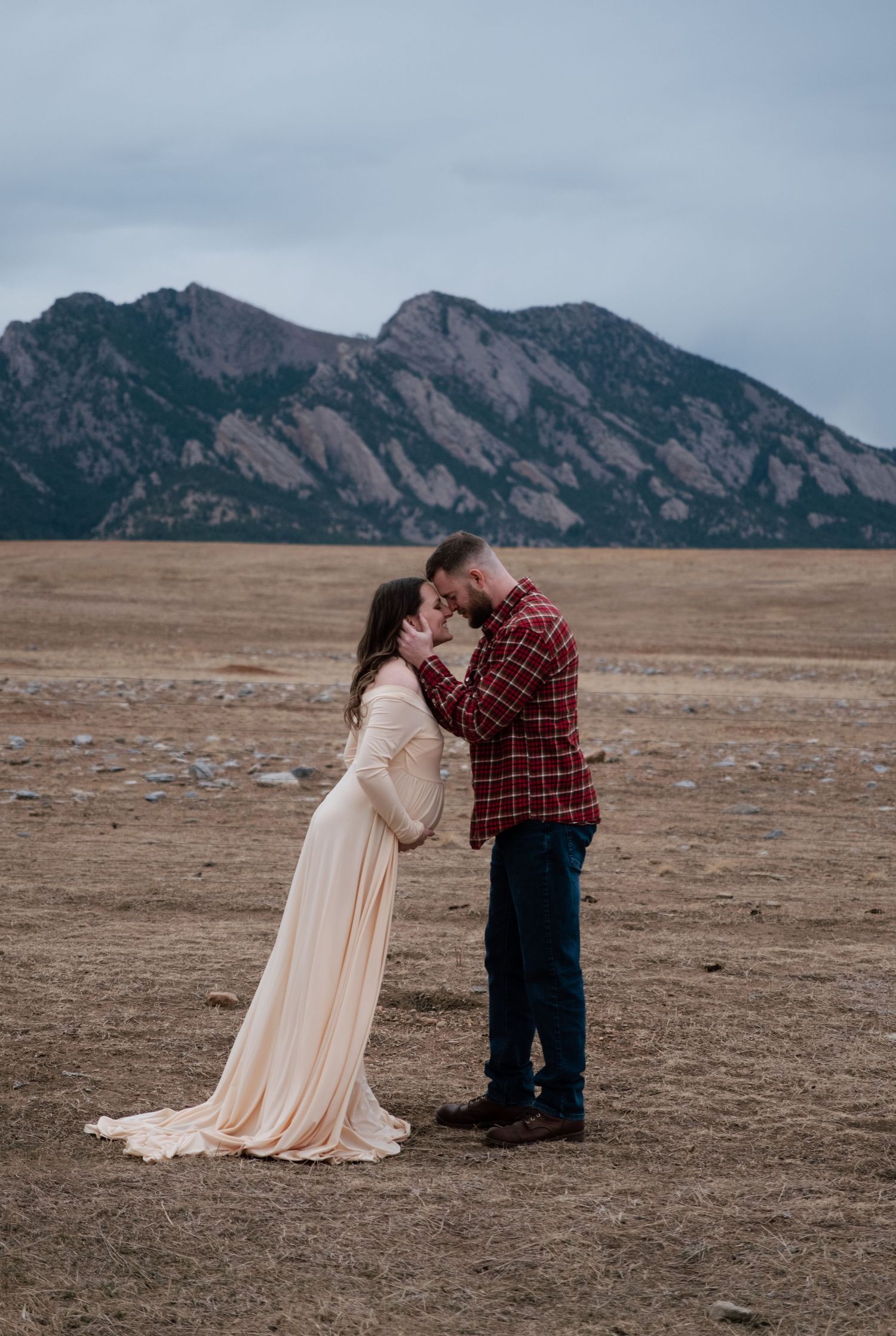 Couple sharing a romantic moment in front of the Flatirons in Boulder, Colorado, woman in flowing gown.