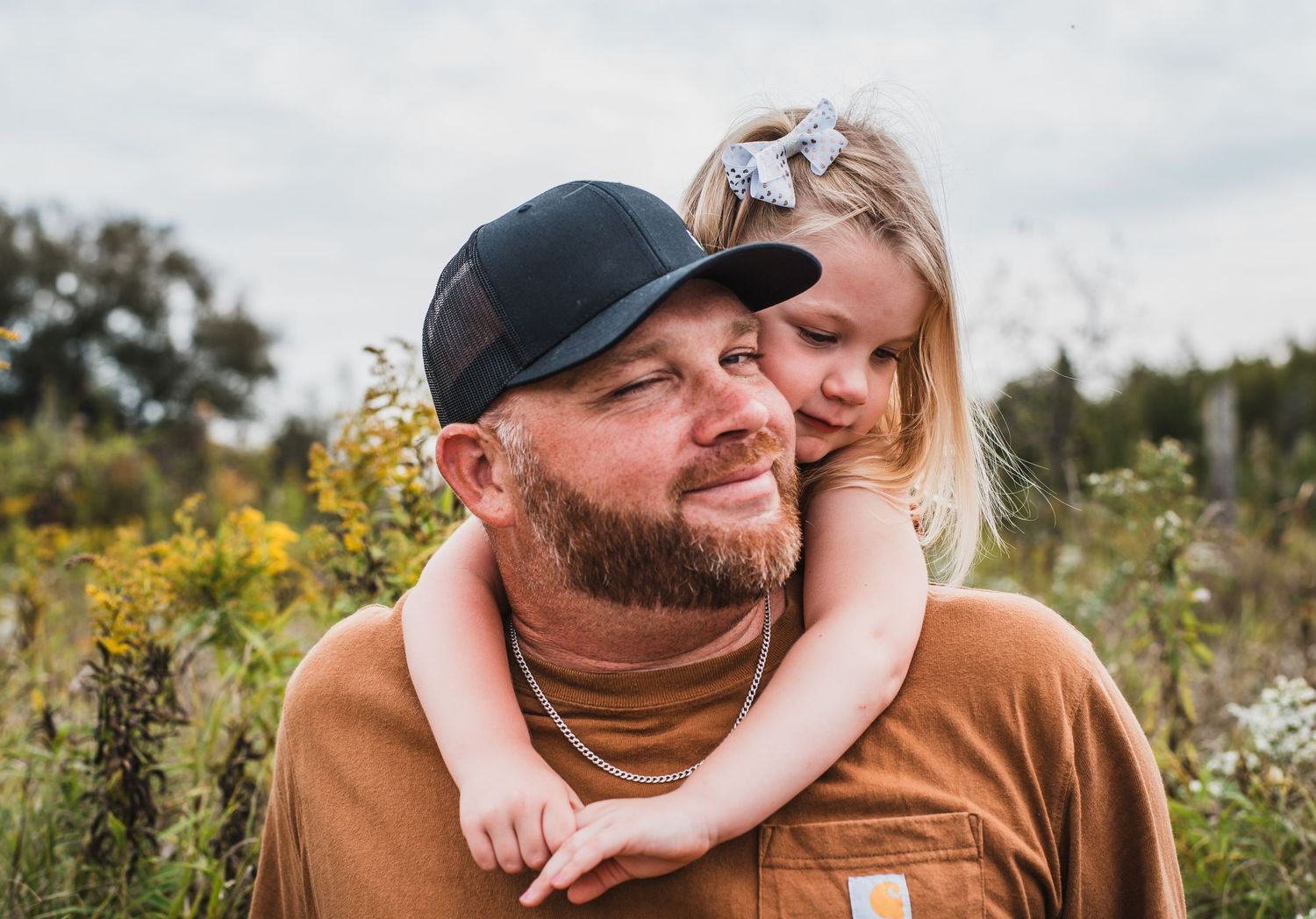 Couple sharing intimate moments outside in a wildflower field with scattered outdoor lifestyle shots.