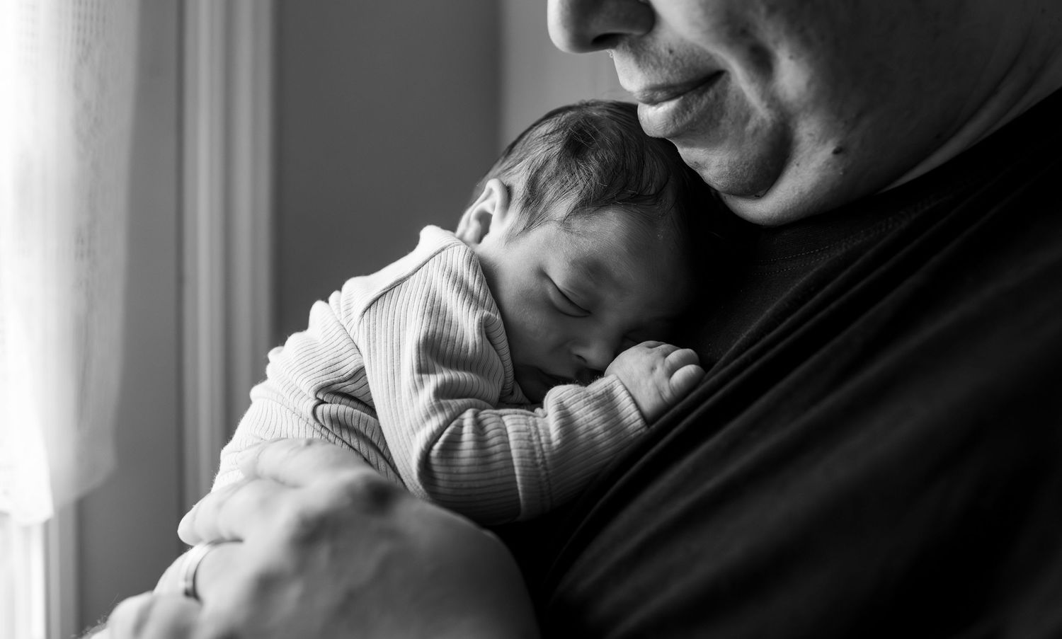 A collage of monochrome images shows closeup portraits of people holding and cradling babies.