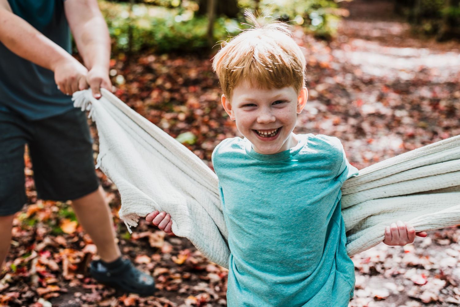 5 sequential photos showing a child in a teal shirt playing and being lifted high into the air in a fall setting outdoors.