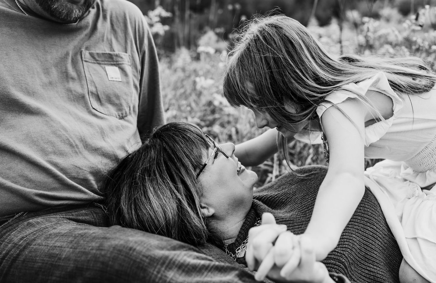 Black and white candid photo of playful and lighthearted moment between two people laying down.