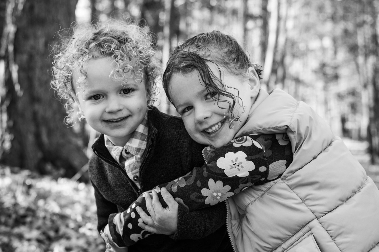 A collection of black and white photographs showing joyful family moments of hugging and embracing outdoors.