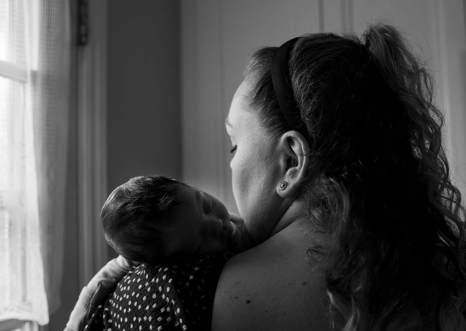 Black and white artistic photo of a couple sharing an intimate moment in a home setting.