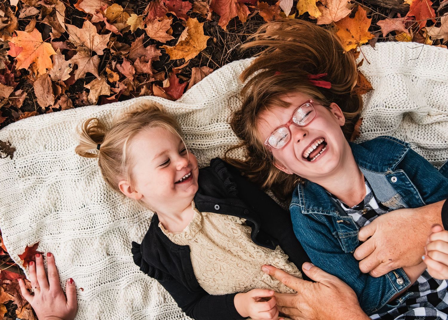 Child laughs while laying on a knitted white blanket wearing a navy blue shirt.