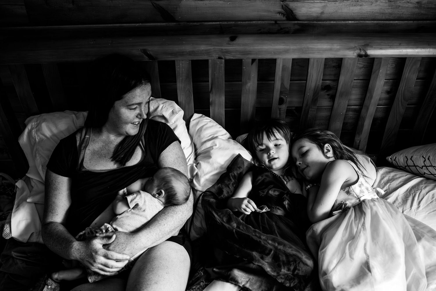 Black and white photo of people relaxing together on a bed while sharing an intimate candid moment.