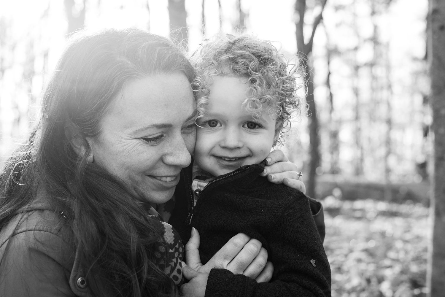 A joyful candid black and white photo collage showing warm family moments shared in a natural outdoor setting.