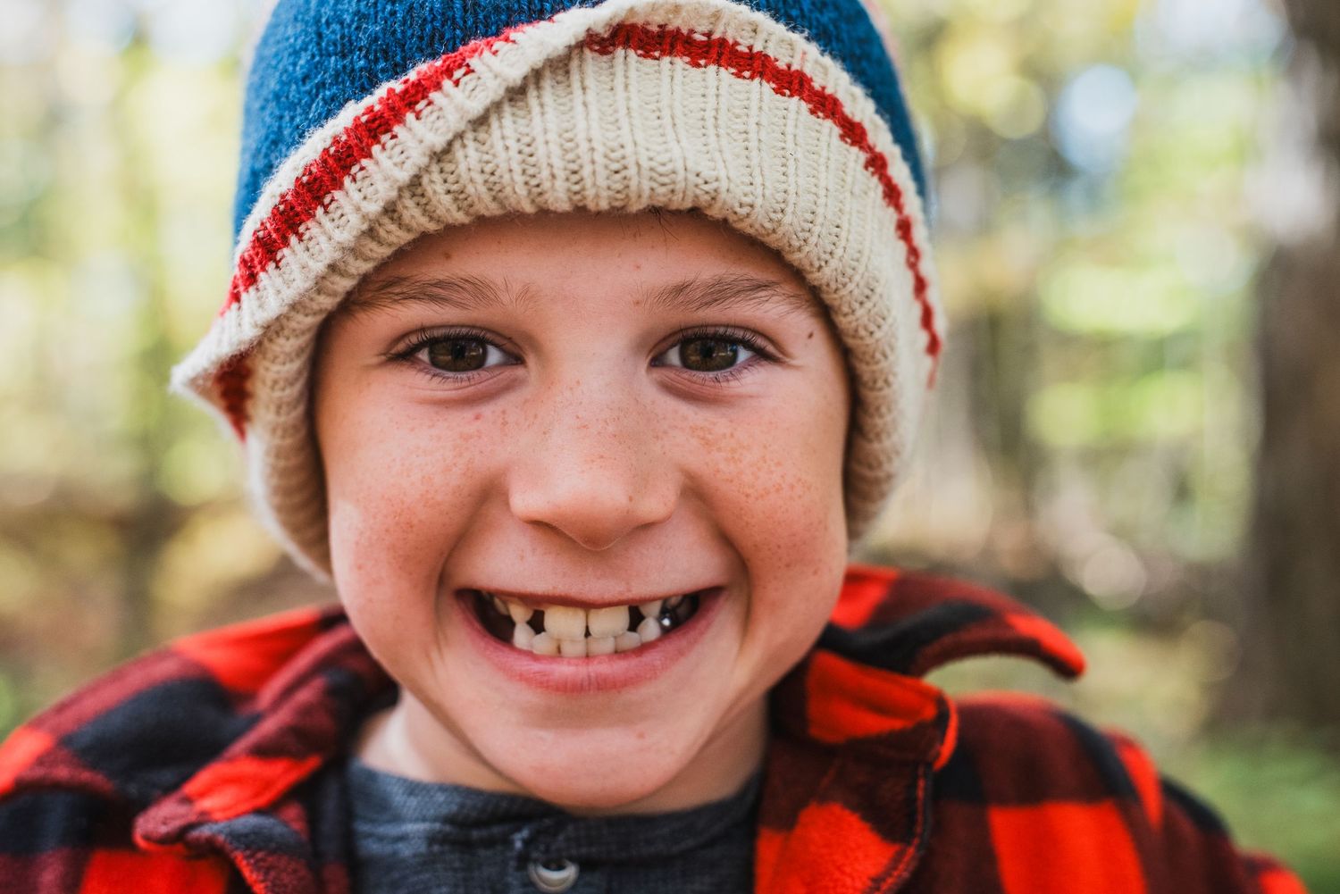 A close-up series of four photos showing someone wearing a red and white striped winter beanie with blurred forest background.