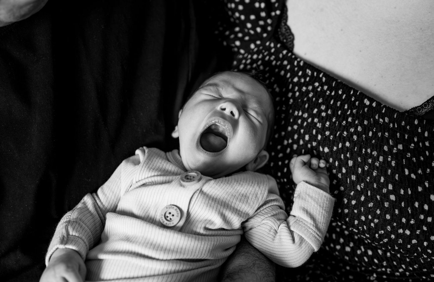 A sleeping infant rests peacefully on polka dot patterned bedding.