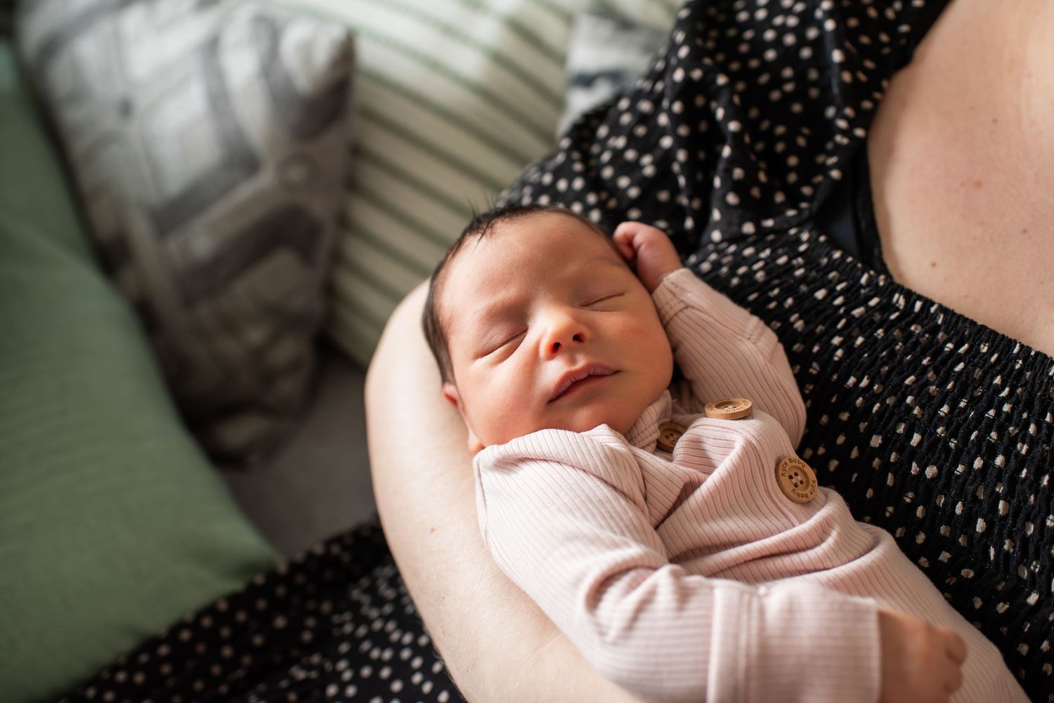 Mother lying down and bonding with newborn baby in intimate home setting.