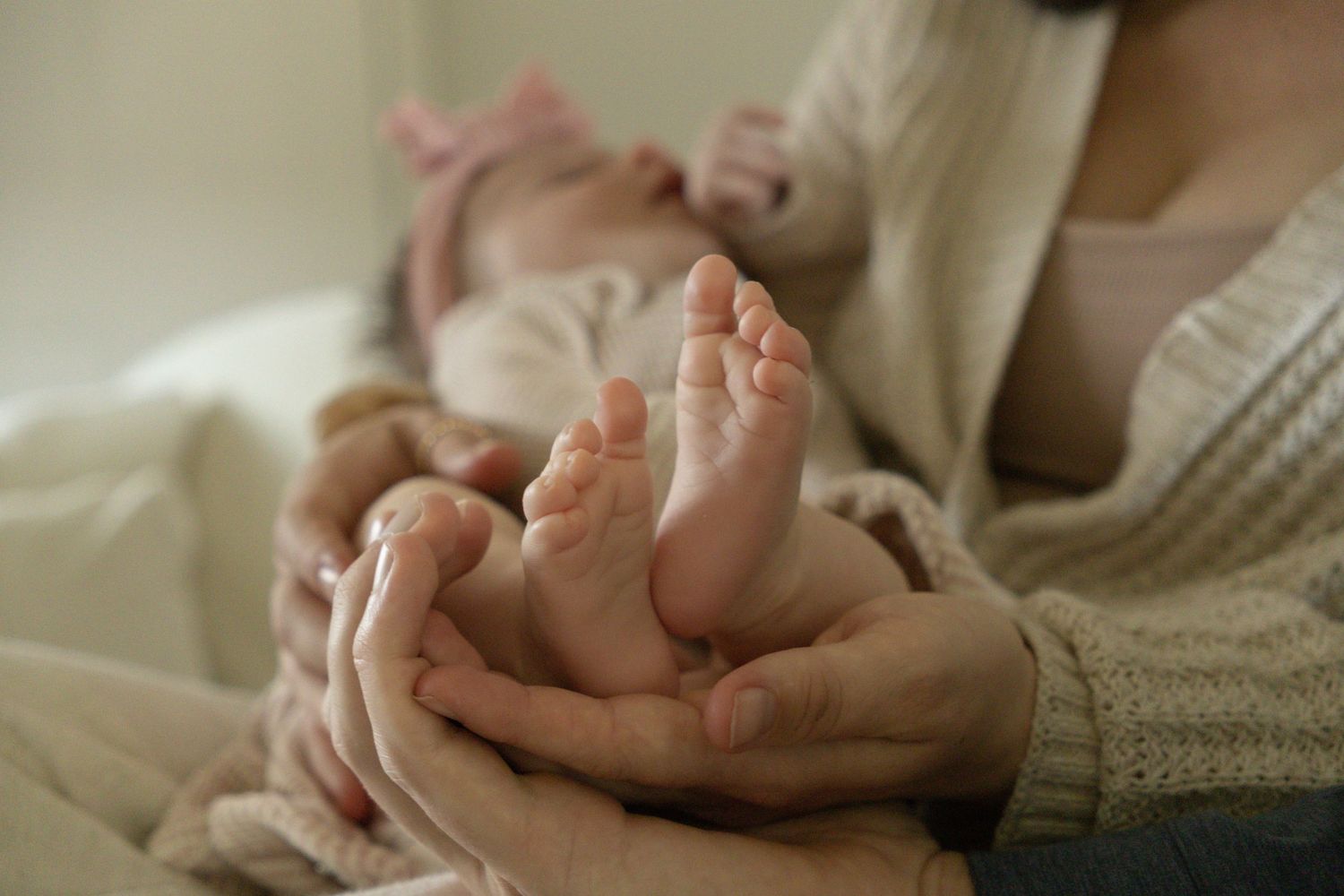 Close-up of newborn baby feet cradled gently in parents hands, soft warm tones.