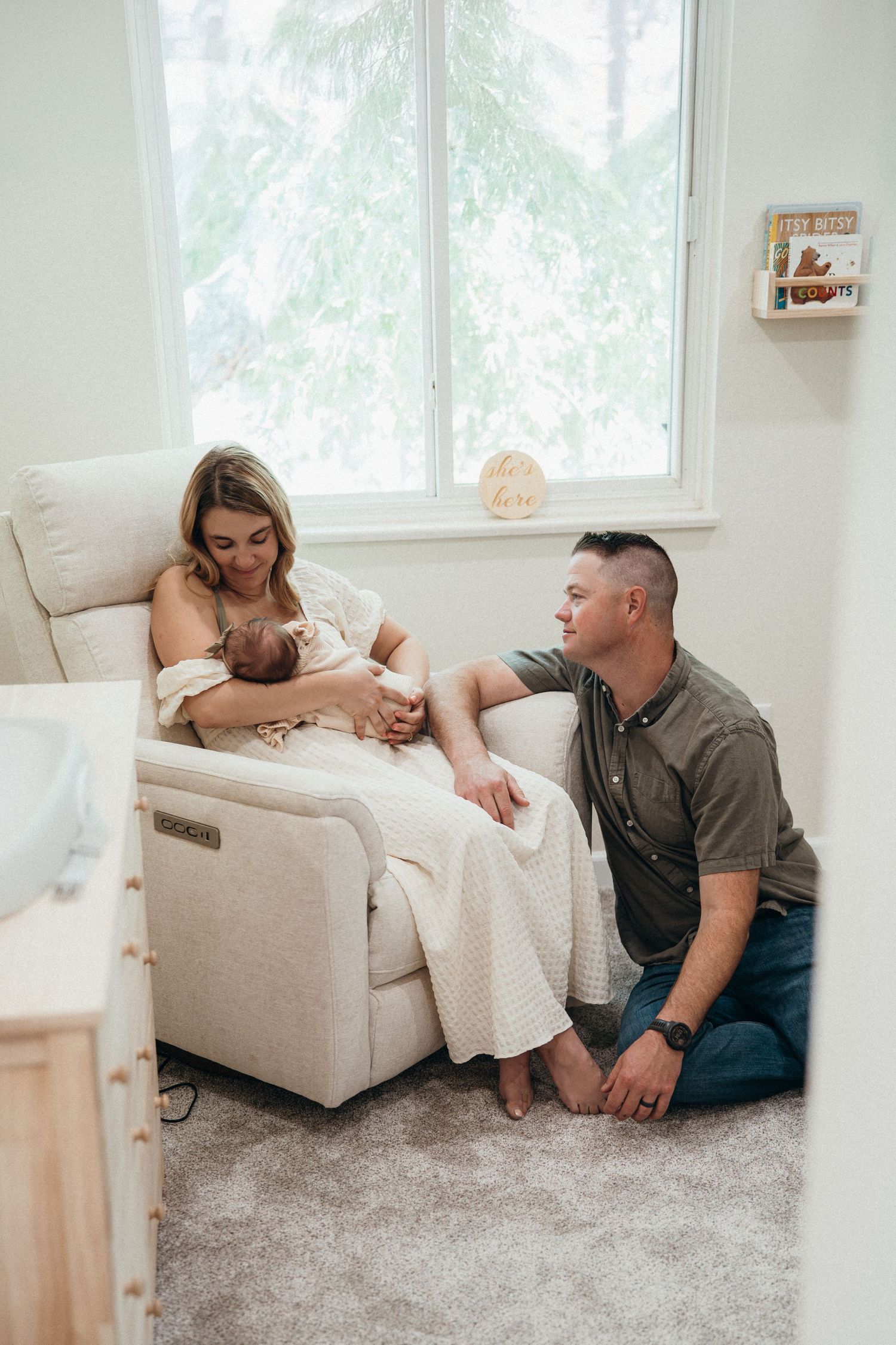 A couple shares an intimate moment while relaxing on a plush carpet in a bright, sunlit living room.