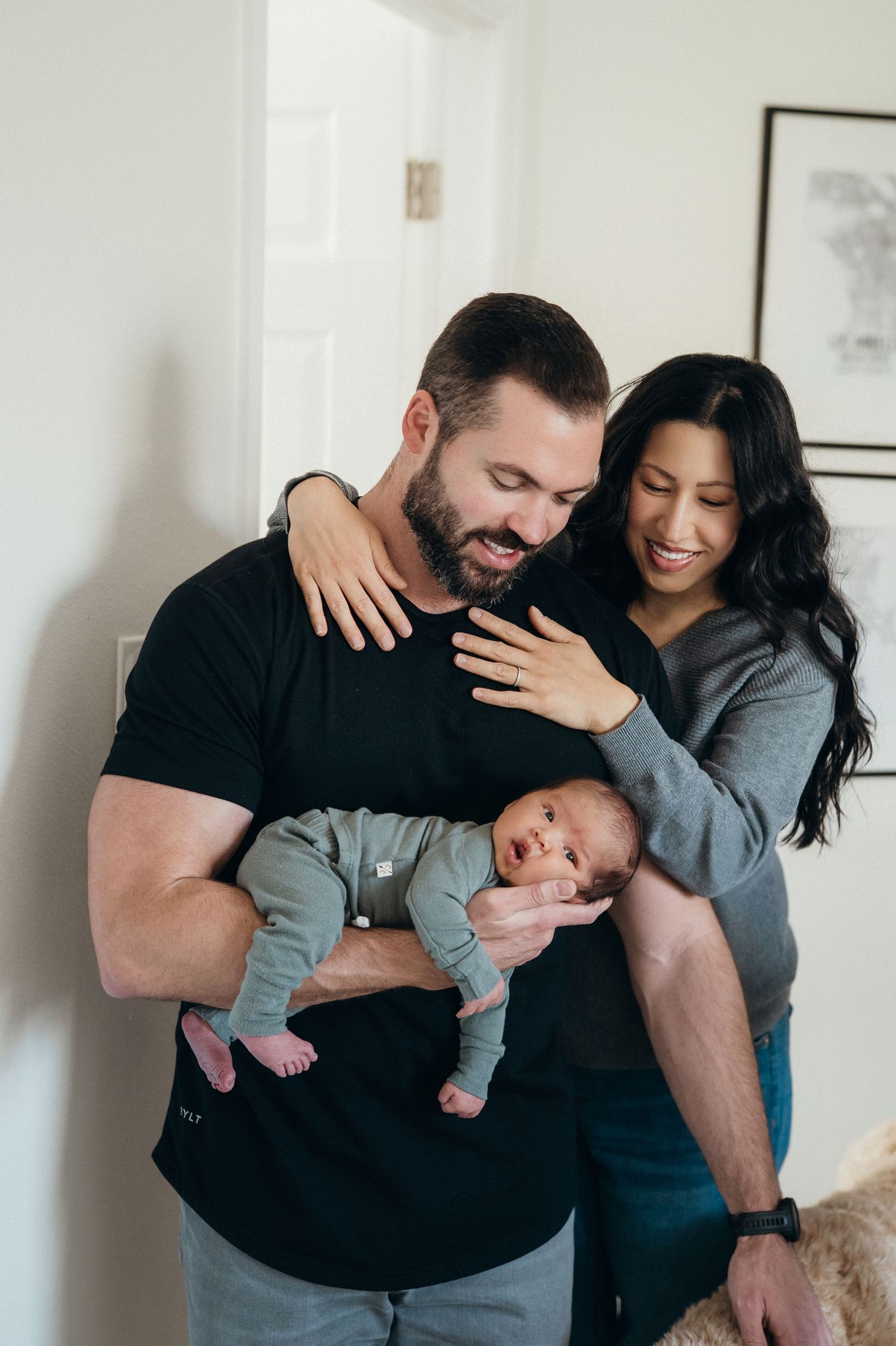A couple shares a joyful moment with their newborn baby in a cozy home setting.