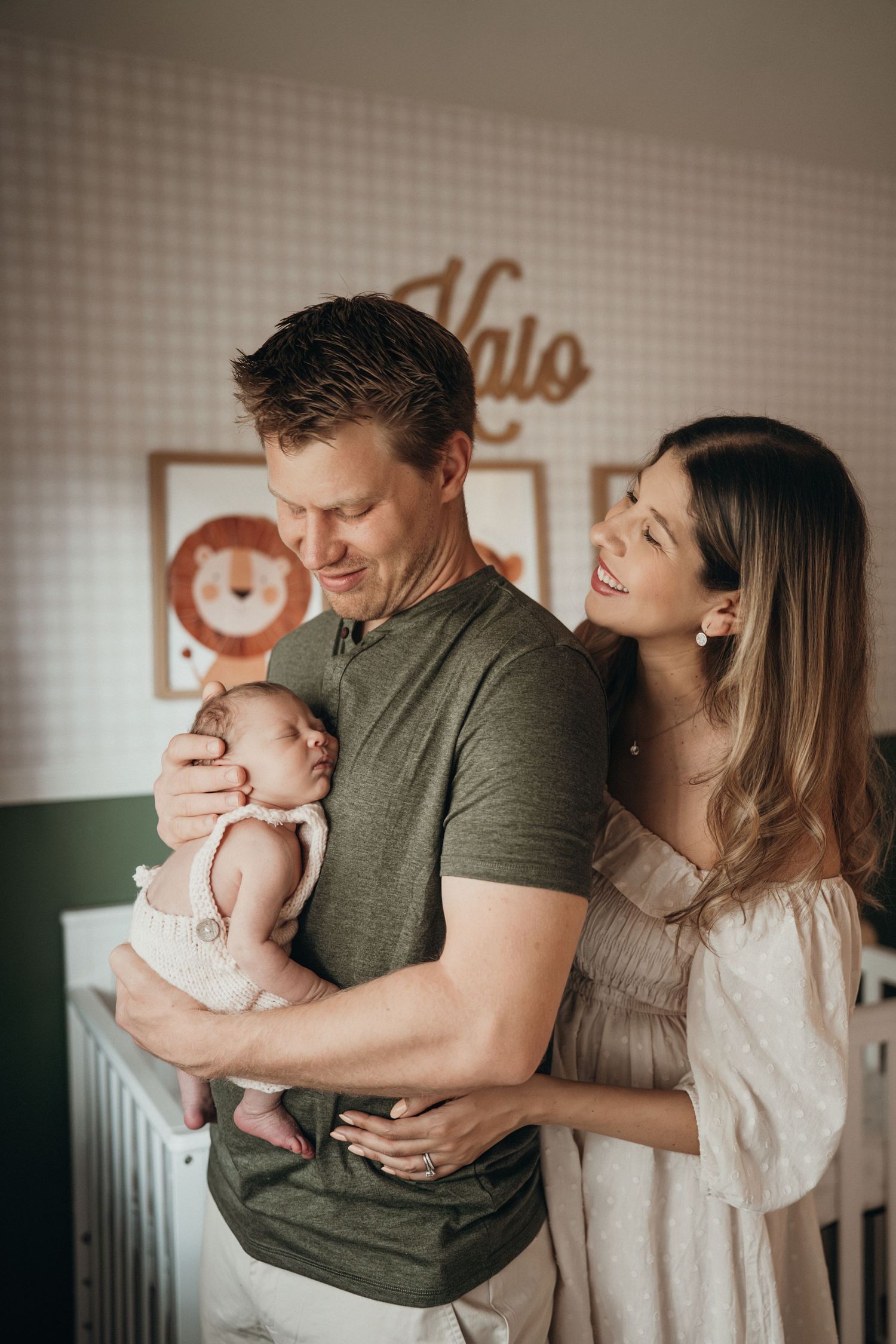 A tender moment is shared in a softly lit room with a newborn baby.