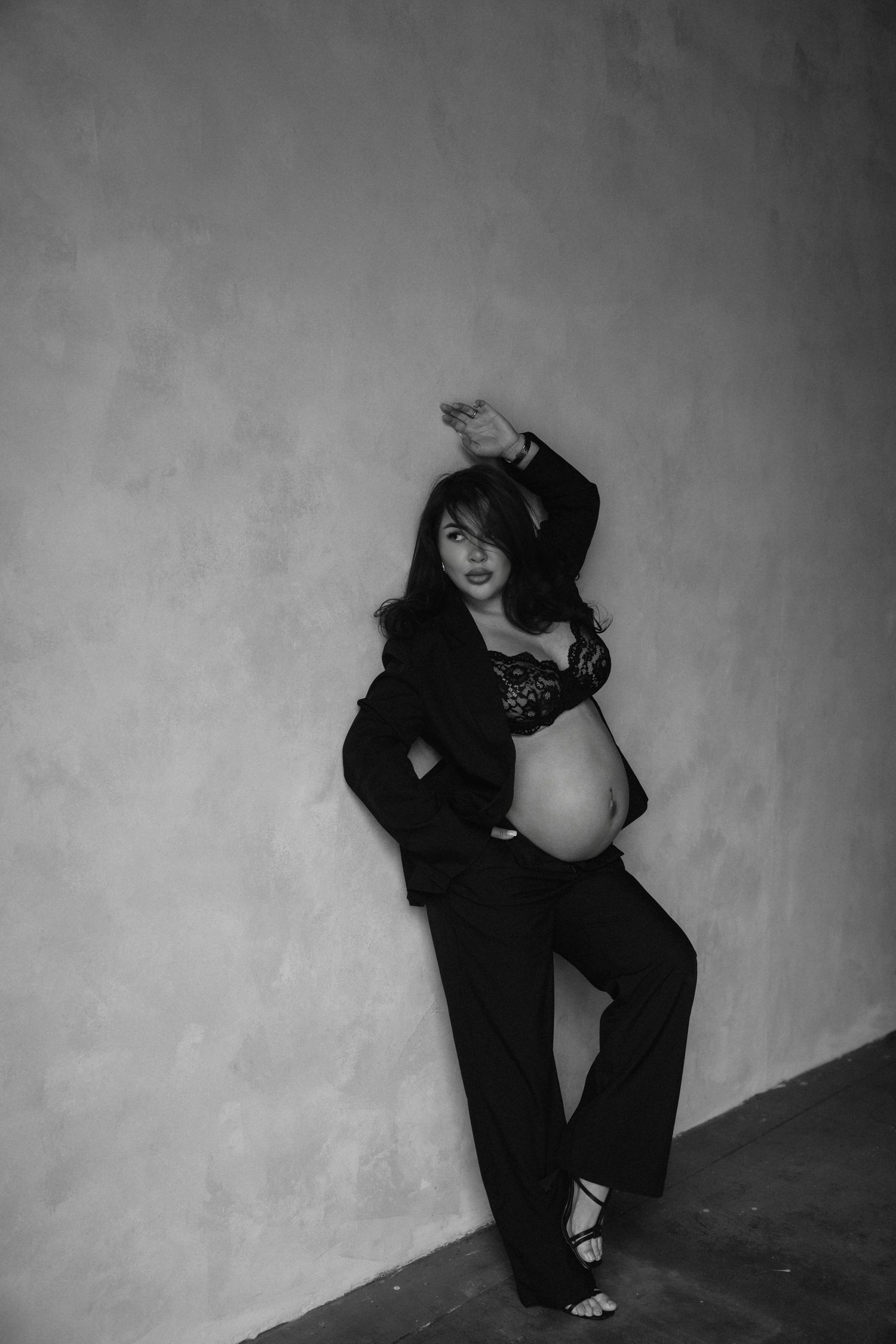 A series of black and white photographs showing a figure in dark clothing crouched against a plain wall.