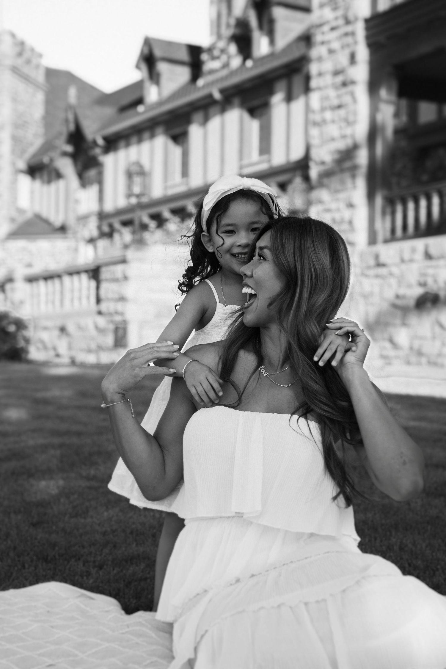 A black and white photo series capturing sweet moments in an outdoor wedding setting with stone buildings in the background.