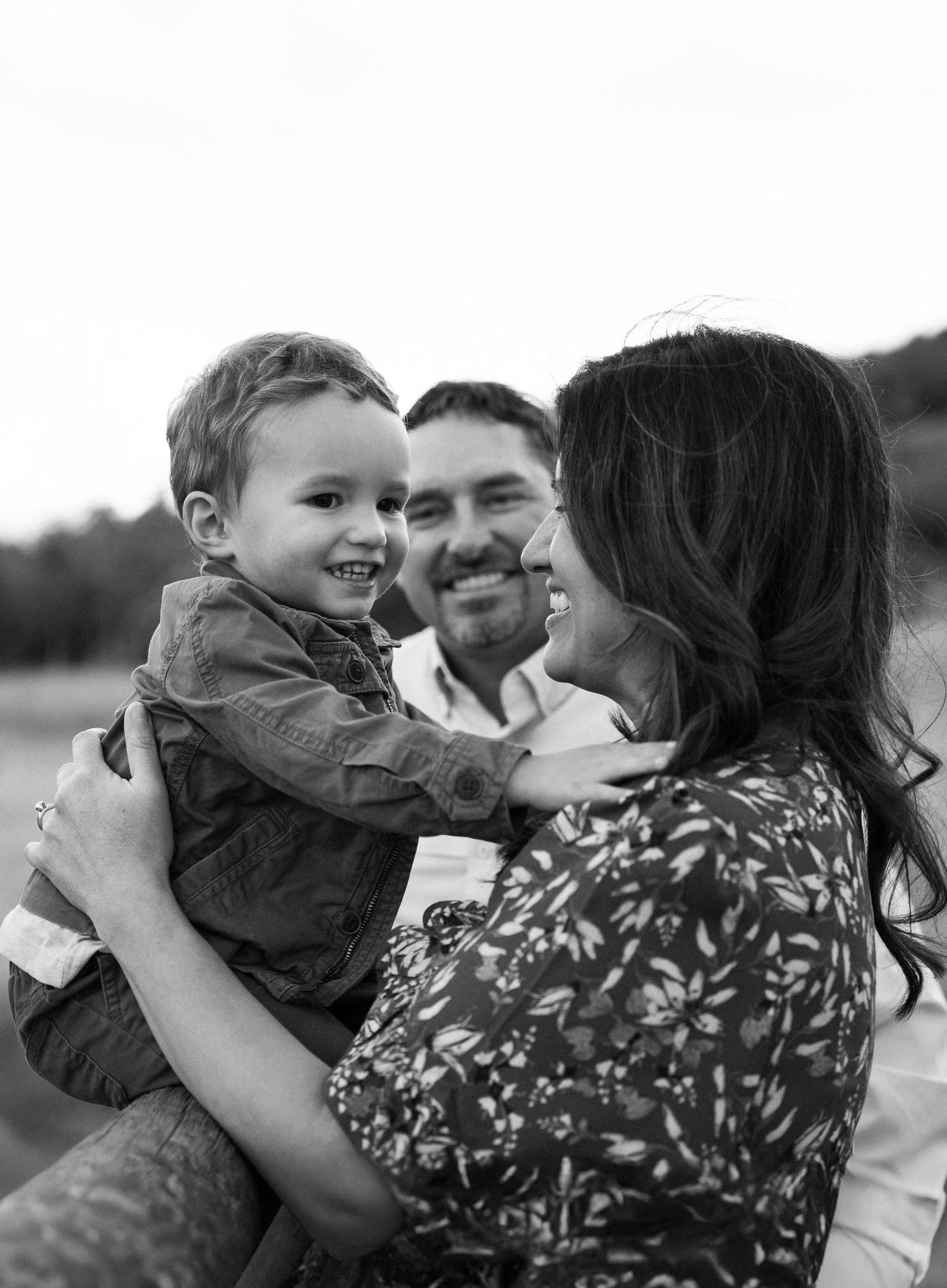 A family shares a joyful moment together outdoors in black and white.