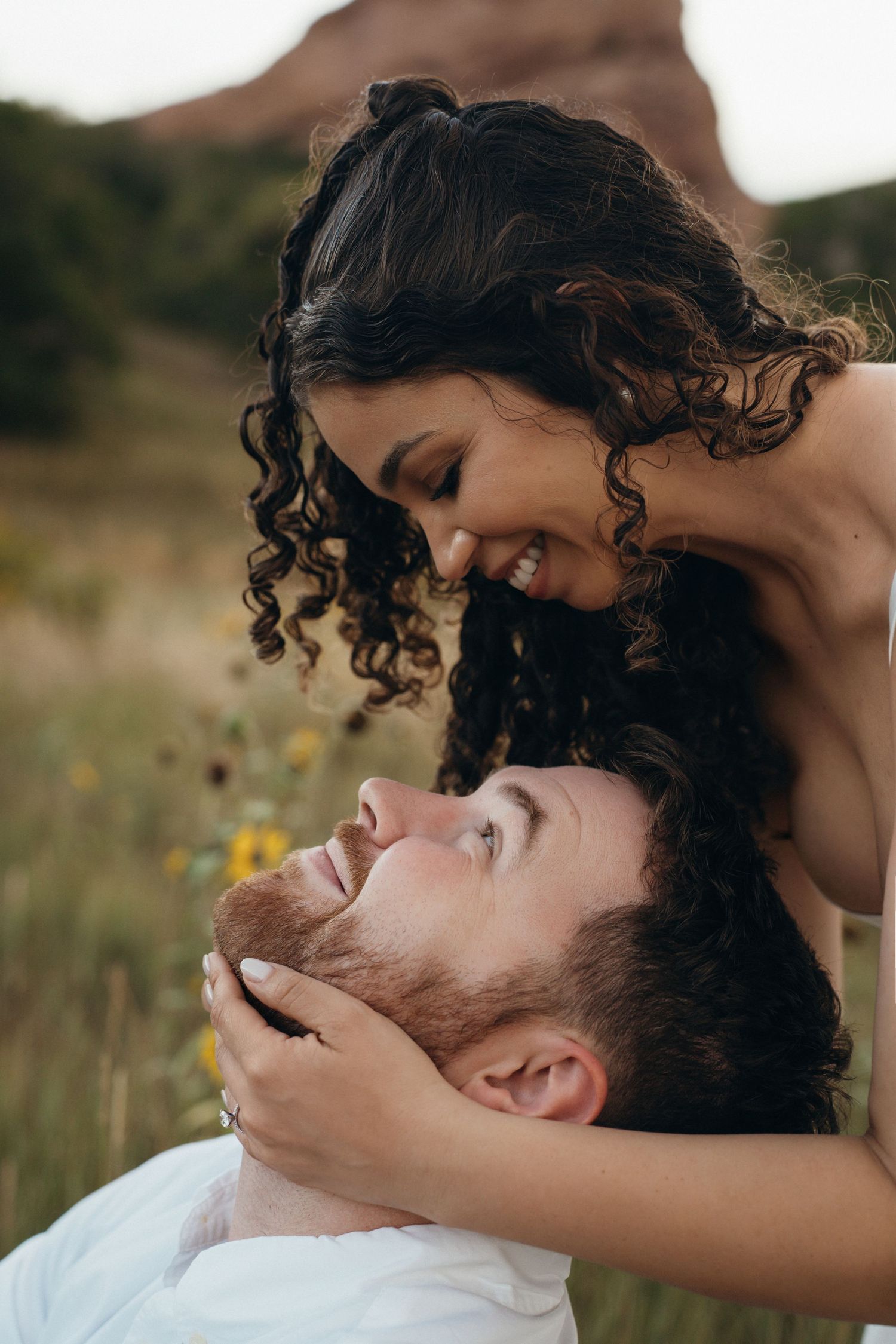 A romantic couple shares an intimate moment in a wildflower field during golden hour.