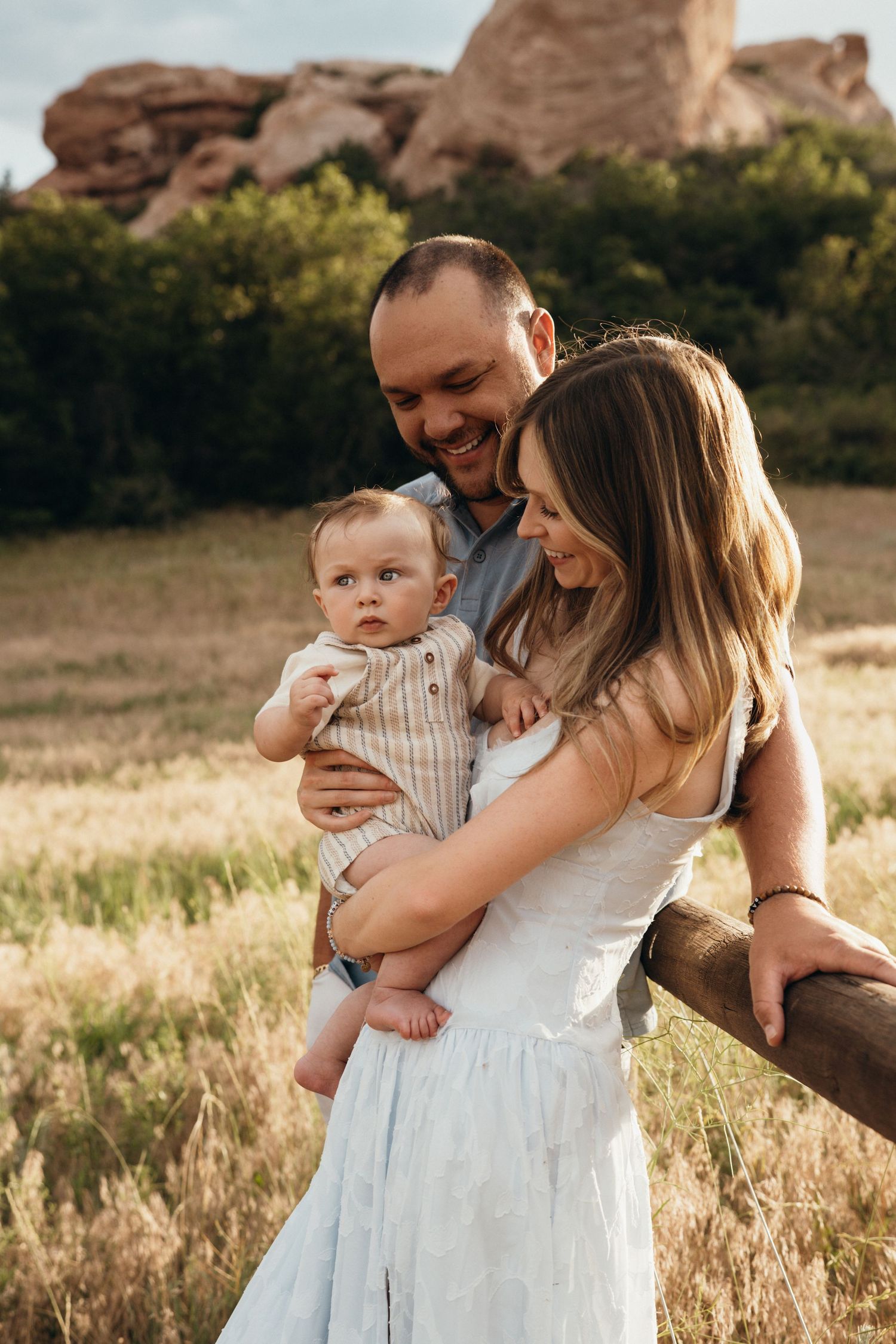 A family shares tender moments in a sunlit field during golden hour.
