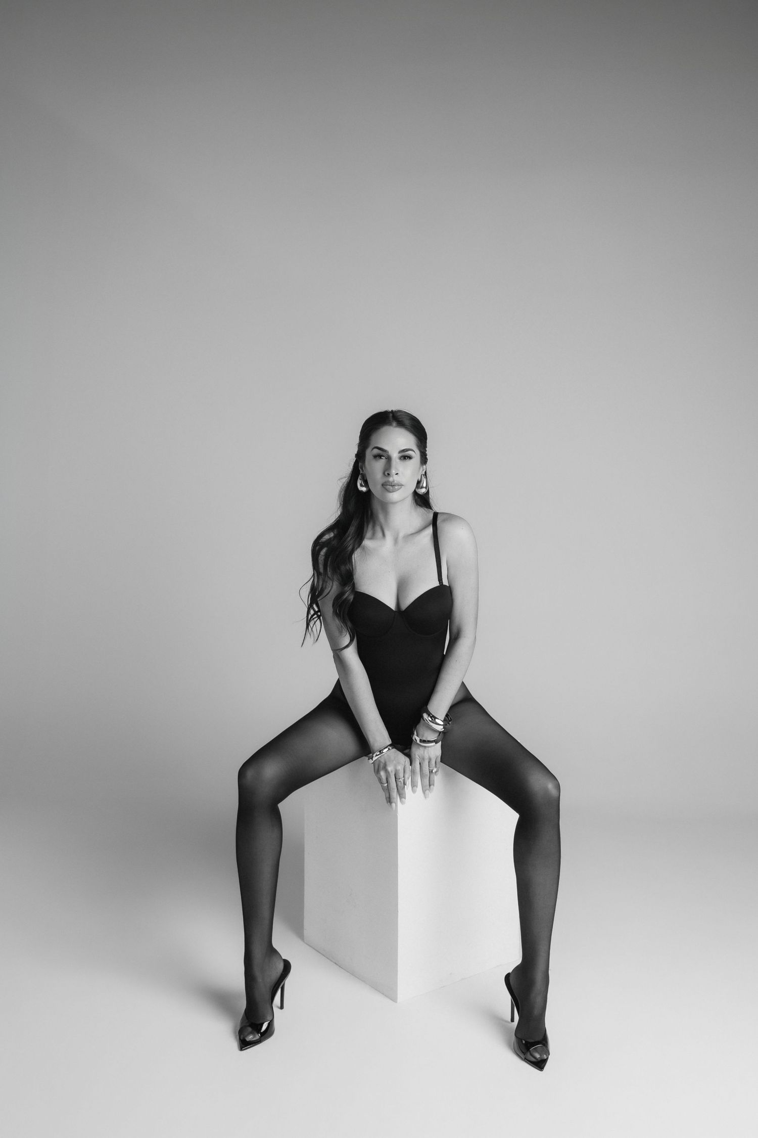 Artistic black and white studio photography series showing figure in black dress posing with geometric white shapes.