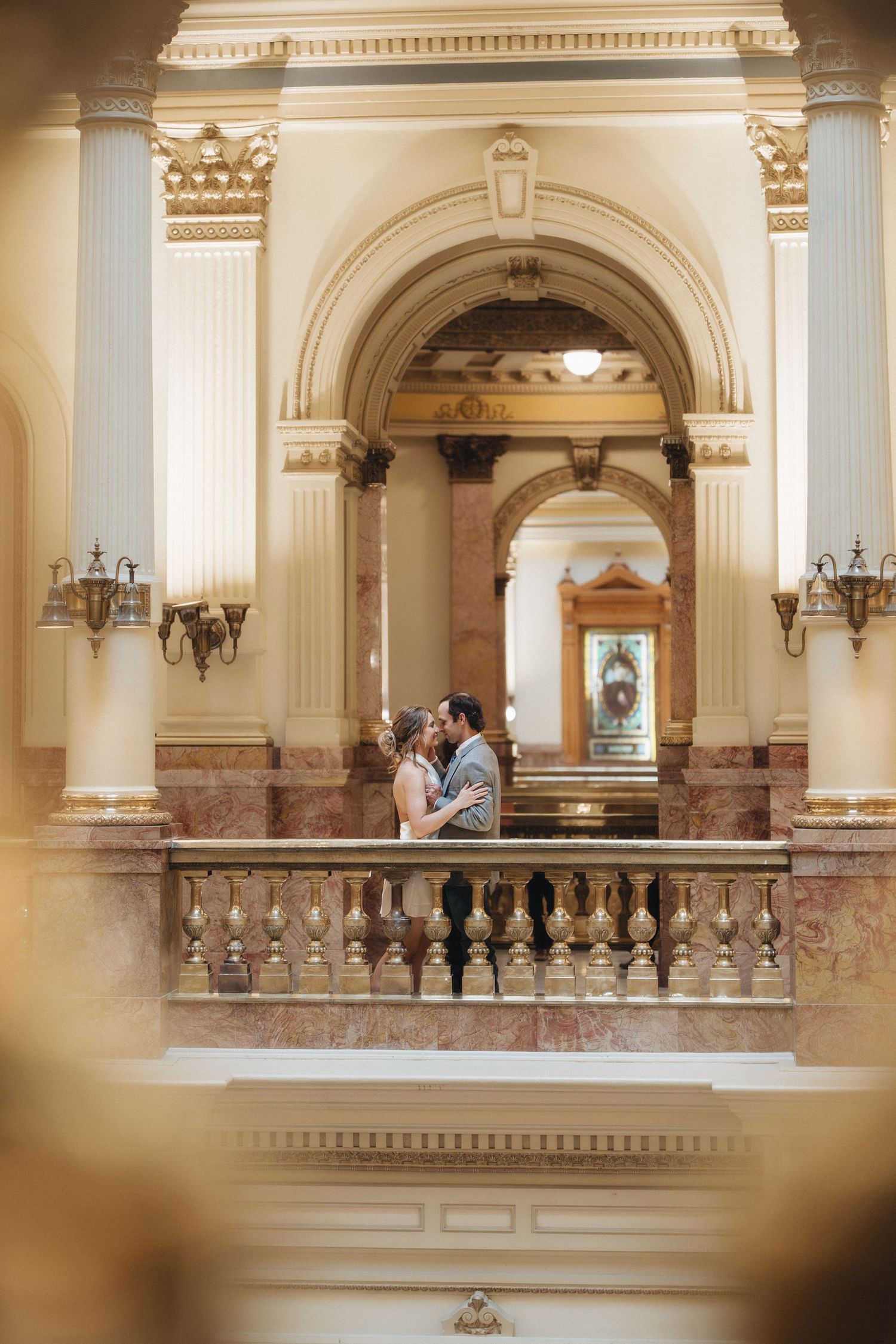 Elegant interior balcony of historic building with ornate white columns, marble details and decorative moldings.