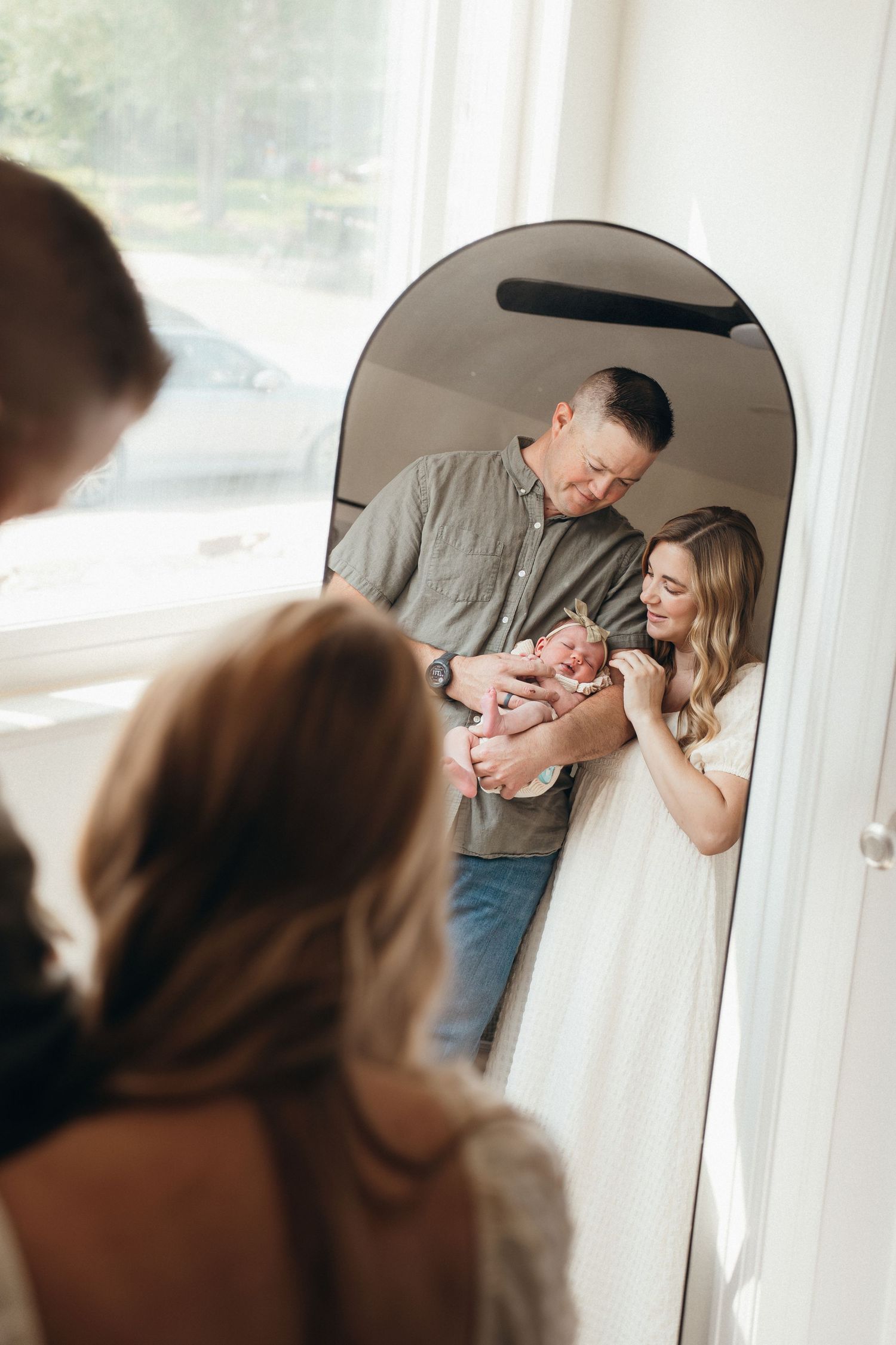 A couple shares an intimate moment while standing near a window in soft natural light.
