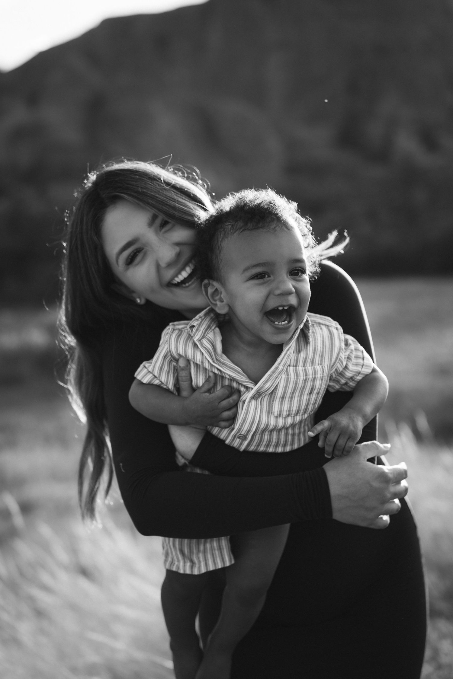 A joyful candid black and white portrait showing a warm embrace and laughter outdoors.