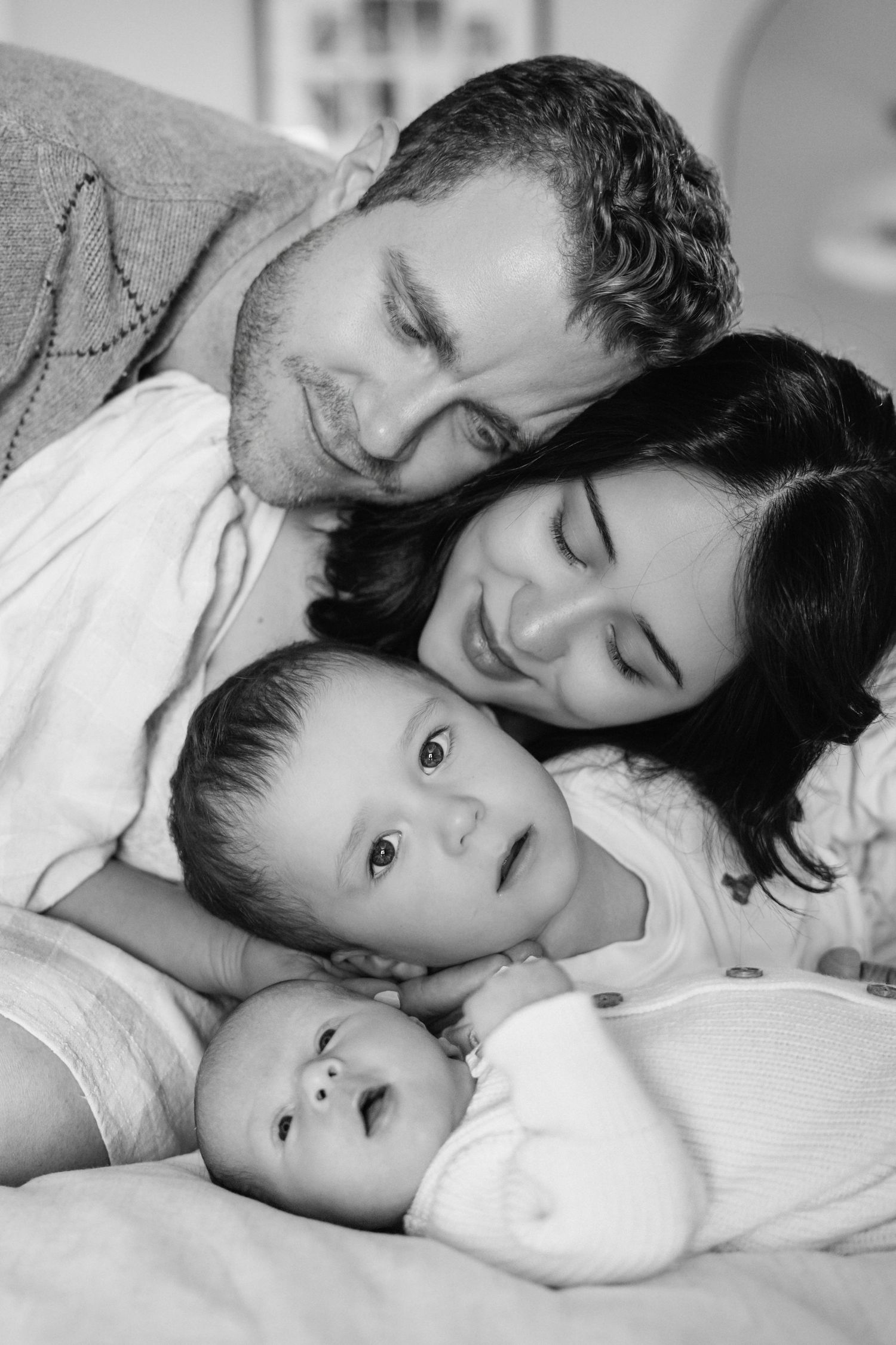 Black and white photo series showing tender moments between parent and child lying together in bed.