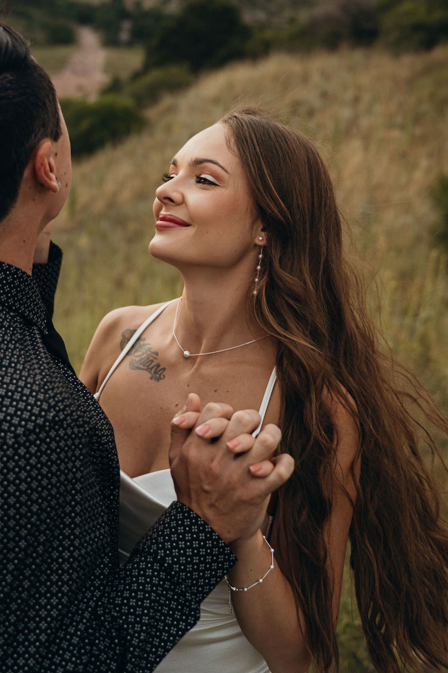 A romantic moment captured between a couple dancing in a field at sunset.