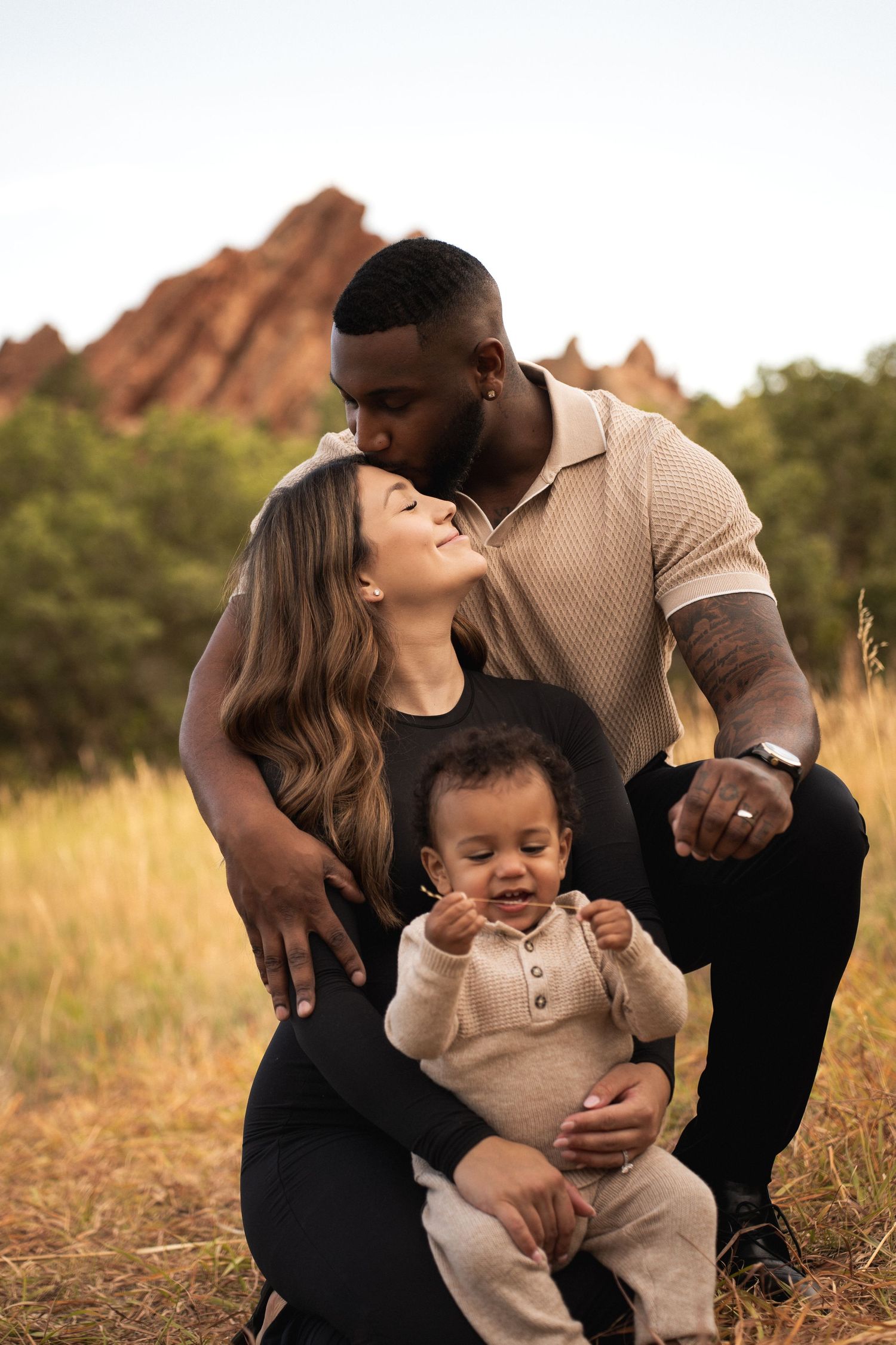 A loving family shares an intimate moment against a backdrop of red rocks during golden hour.