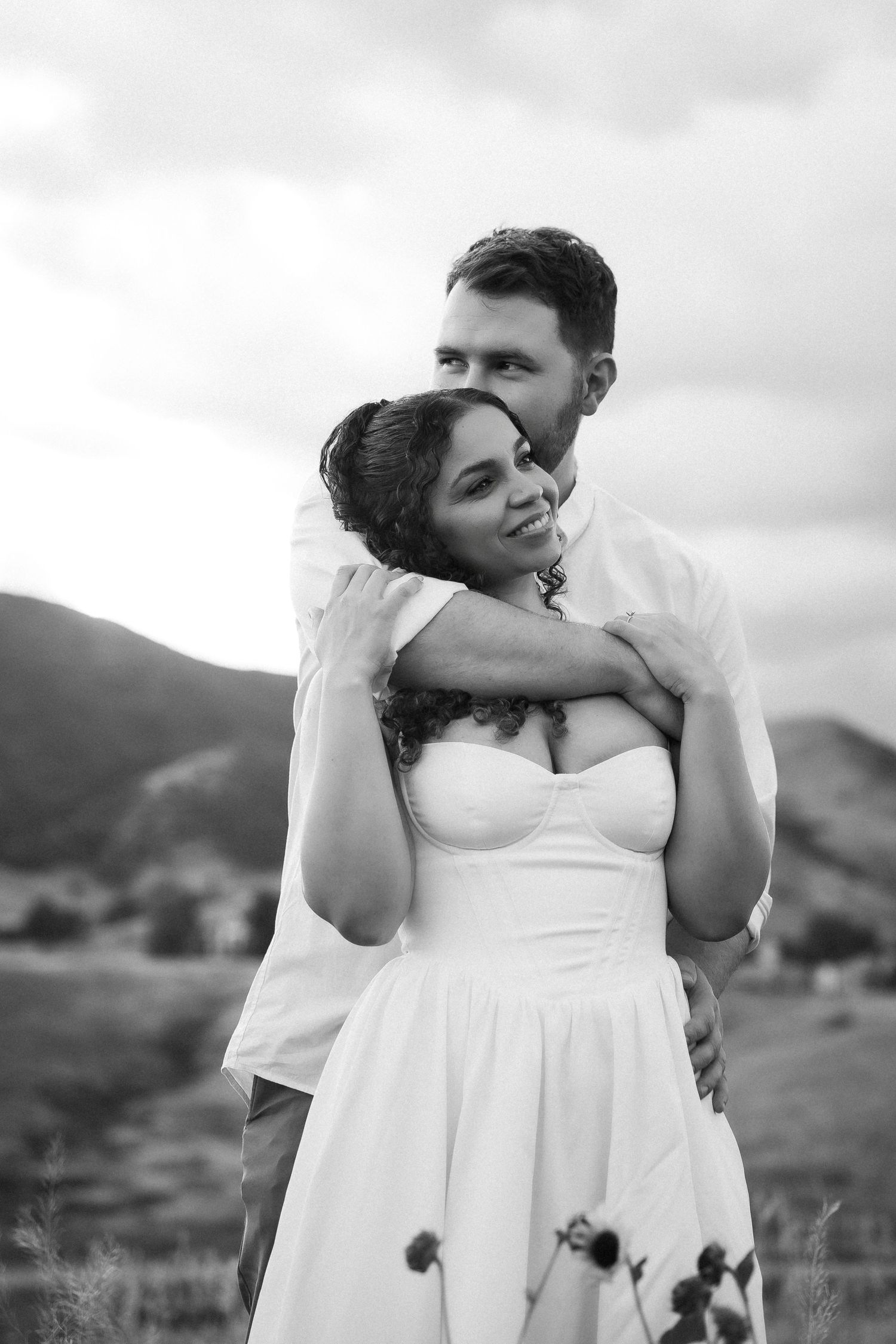A romantic black and white wedding photo series showing an intimate embrace against a mountainous backdrop.