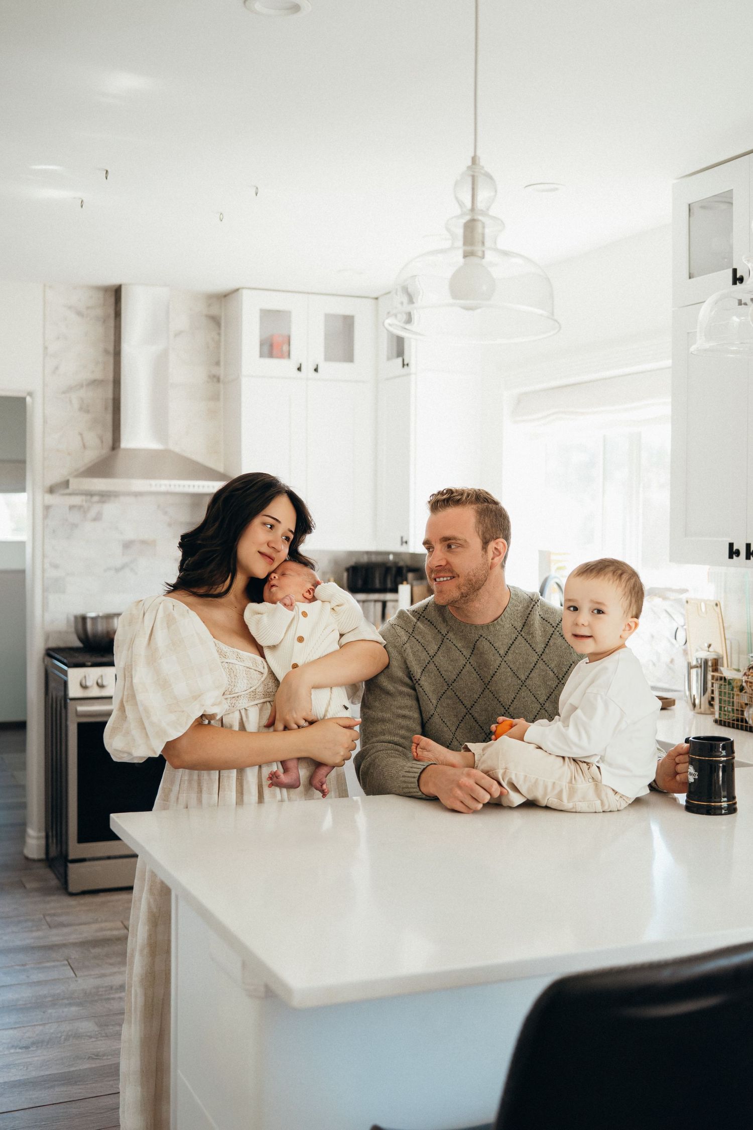 A family shares tender moments together while relaxing in their bright, modern white kitchen.