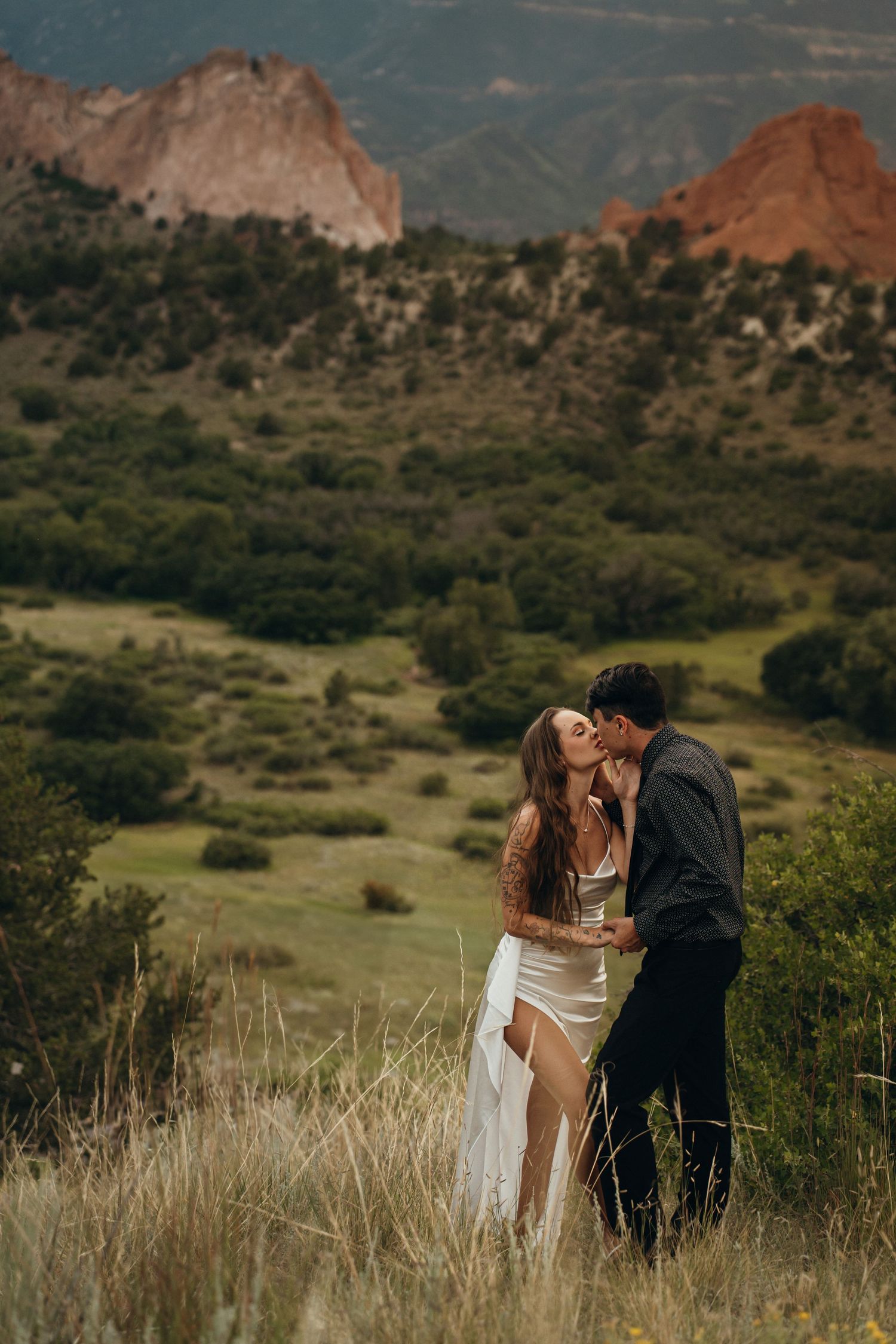 A romantic moment captured between two people in elegant attire against a backdrop of Garden of the Gods in Colorado.