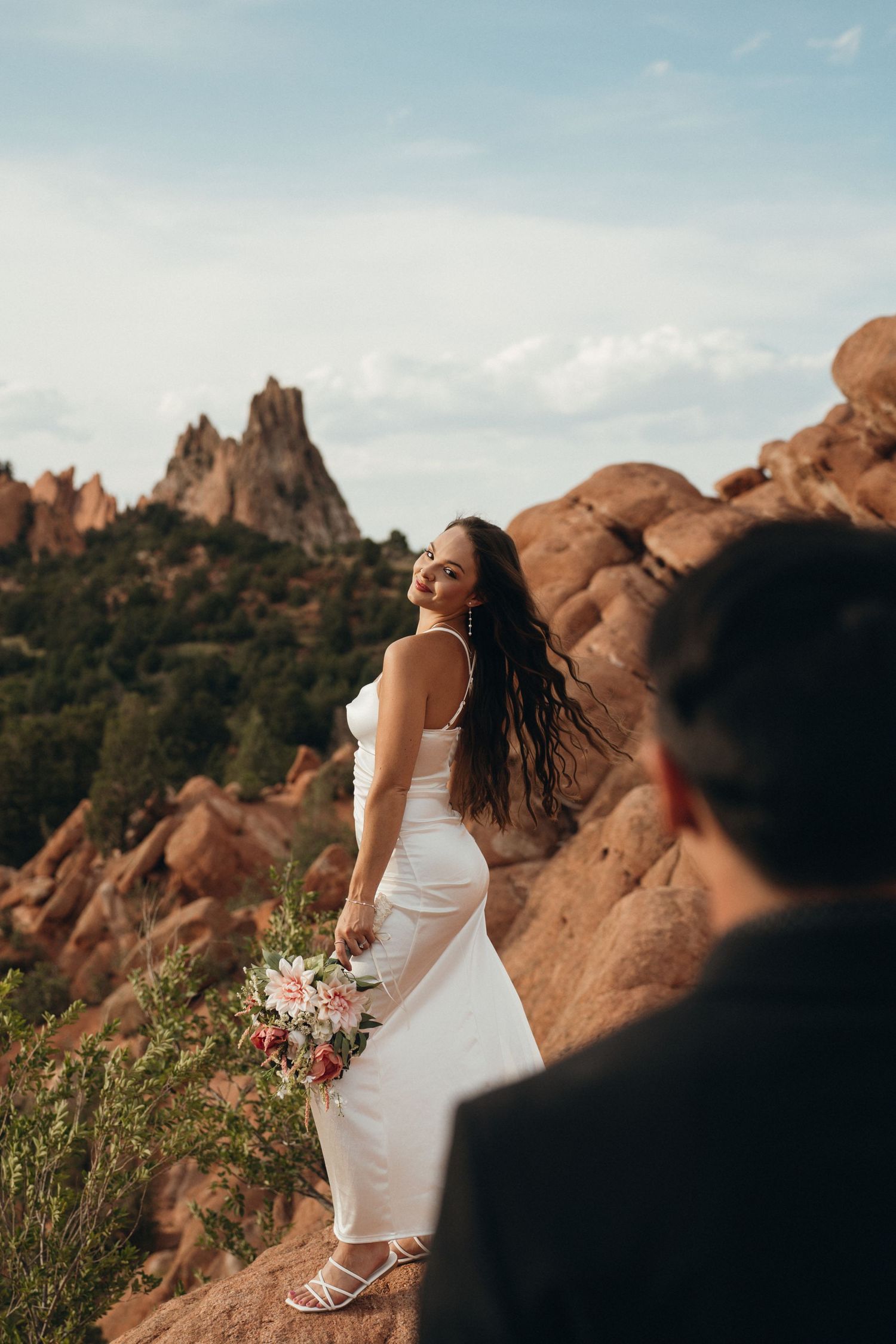 A white dress and bouquet contrast beautifully against dramatic red rock formations in an outdoor setting.