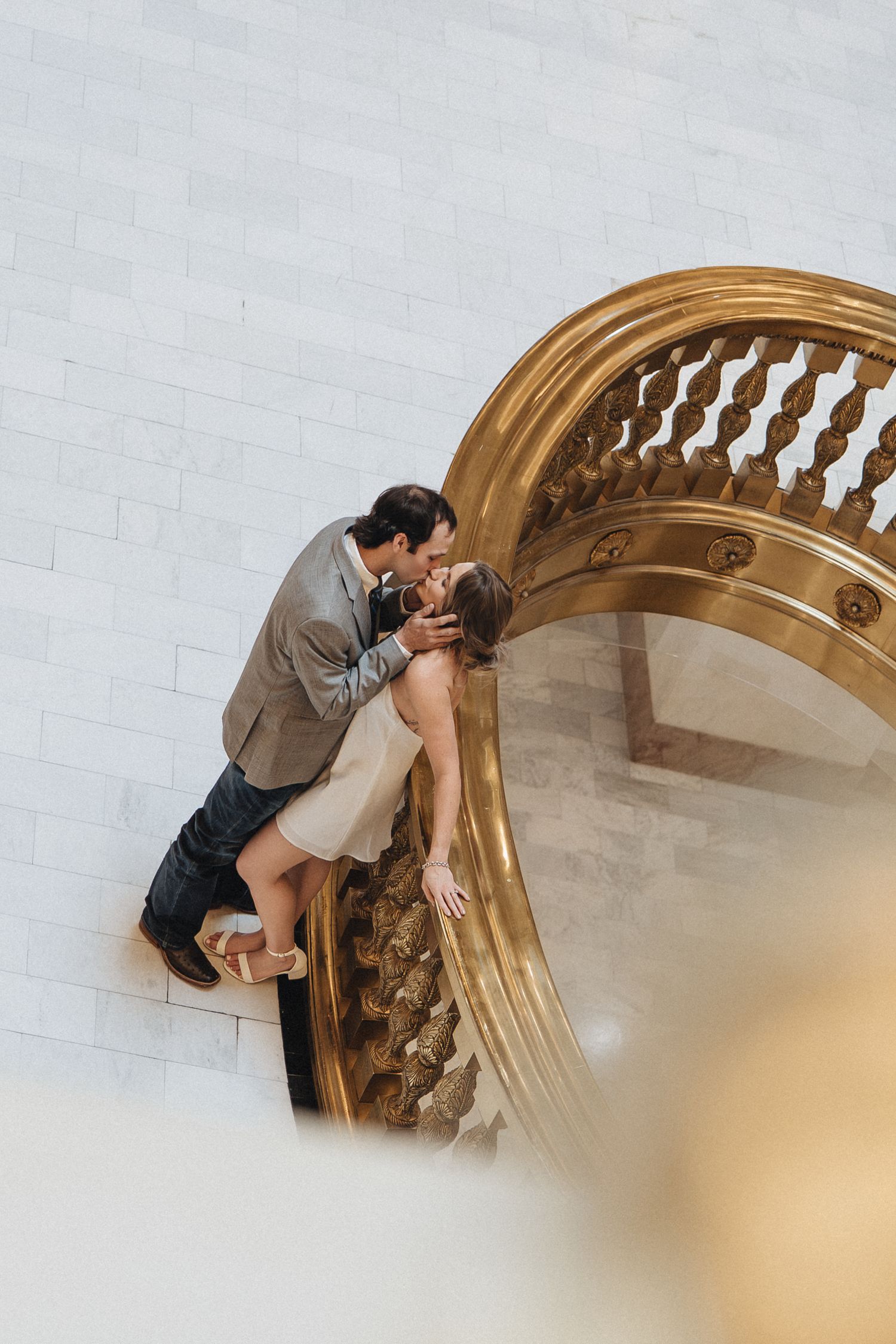 A couple shares a romantic kiss while posing against an ornate gold-trimmed archway in a sequence of photos.