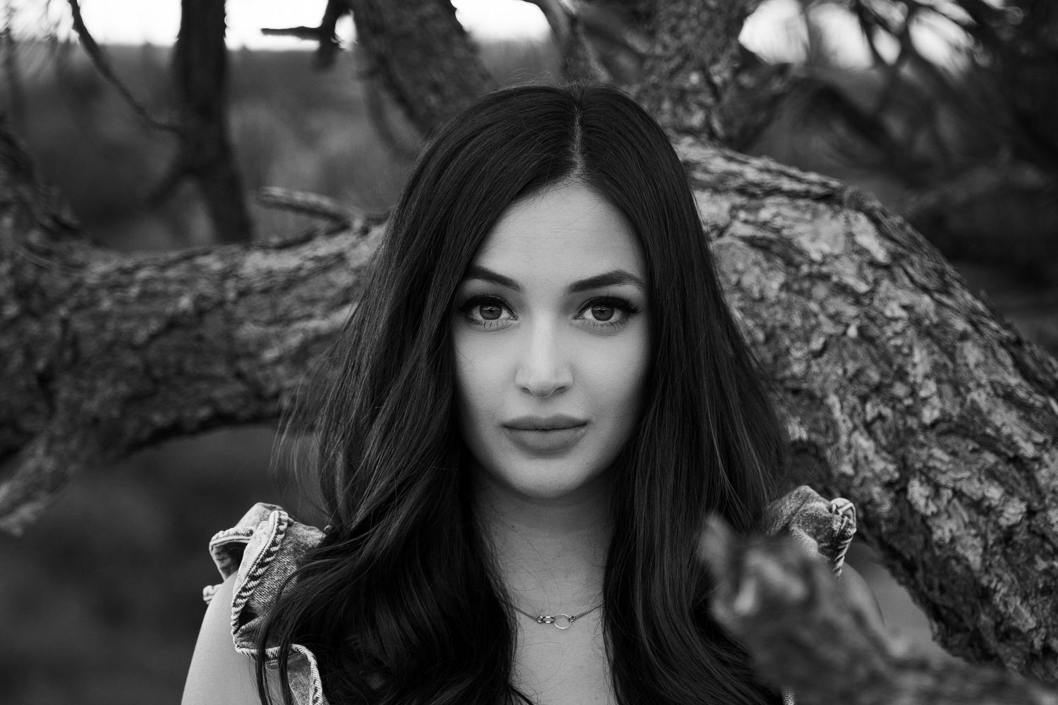 Black and white close-up portrait showcasing long dark hair and delicate jewelry.