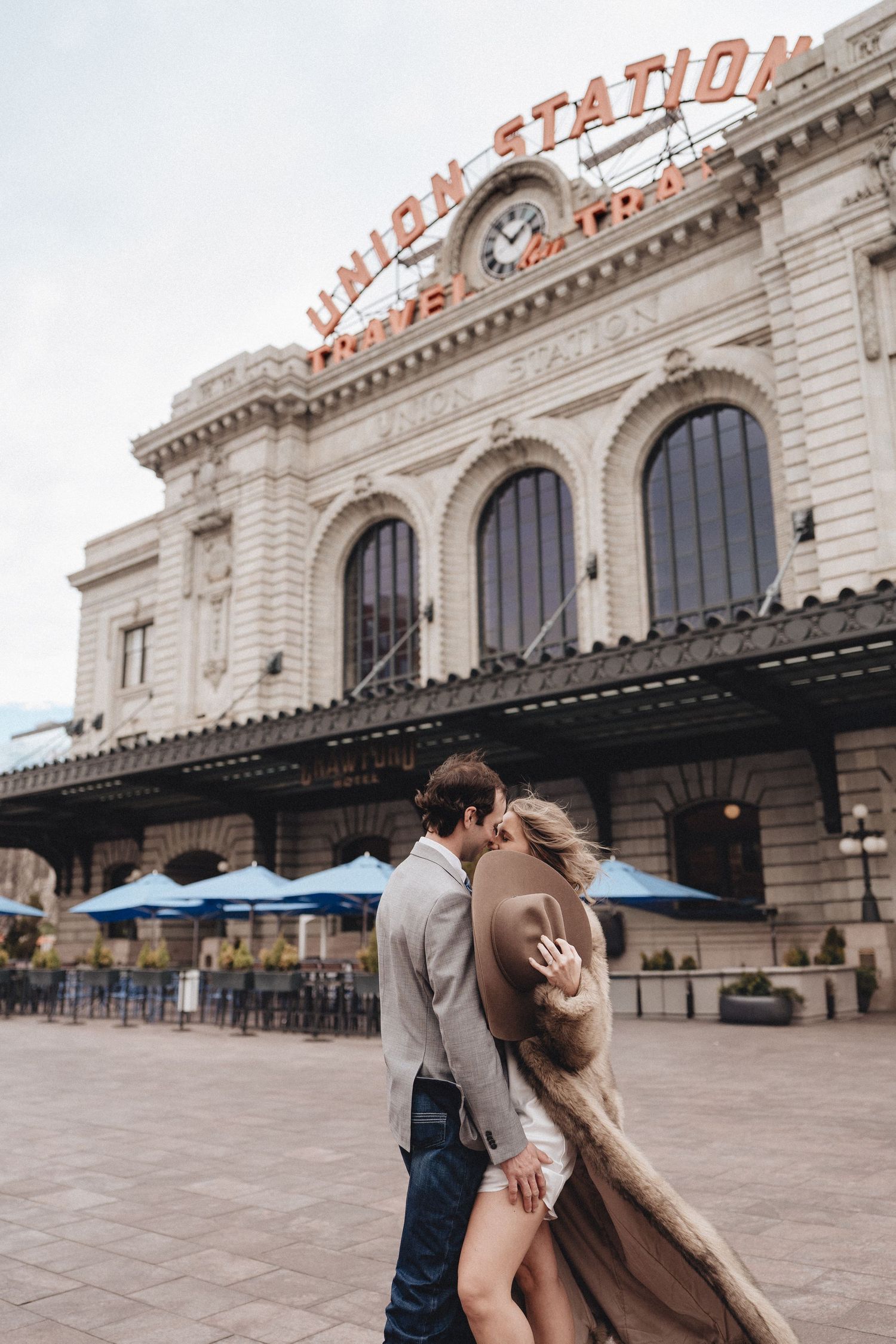 A couple embraces in front of the historic Union Station building with its distinctive signage and architecture.