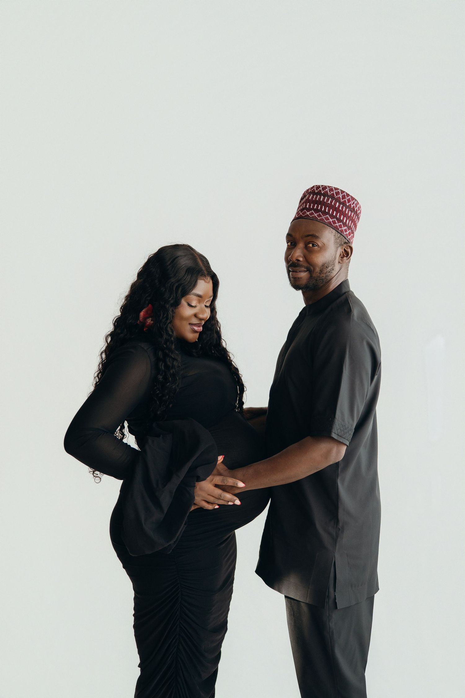 A couple in black outfits sharing a joyful moment together in a photo series against a light background.