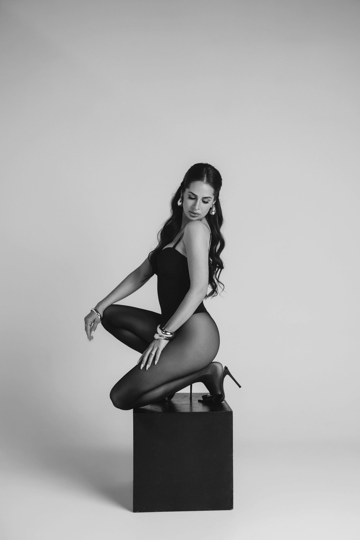 Black and white artistic photo series showing graceful poses on a dark cube against a light background.