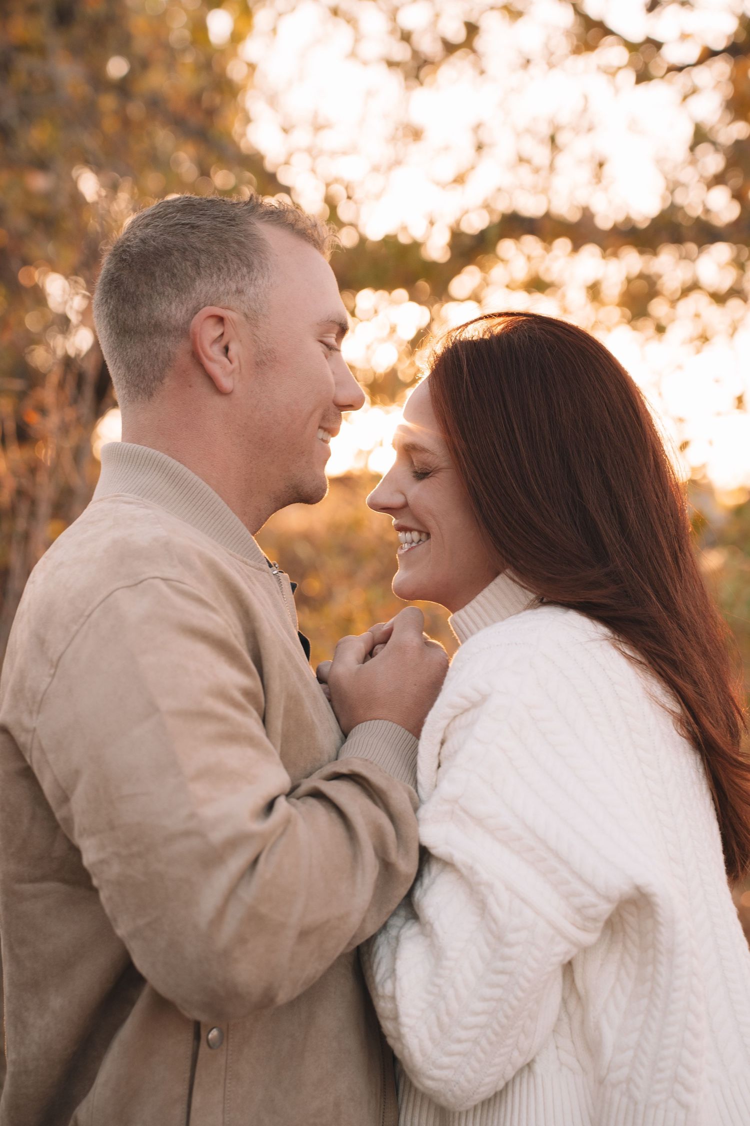 Romantic couple embracing and smiling during golden hour in autumn.