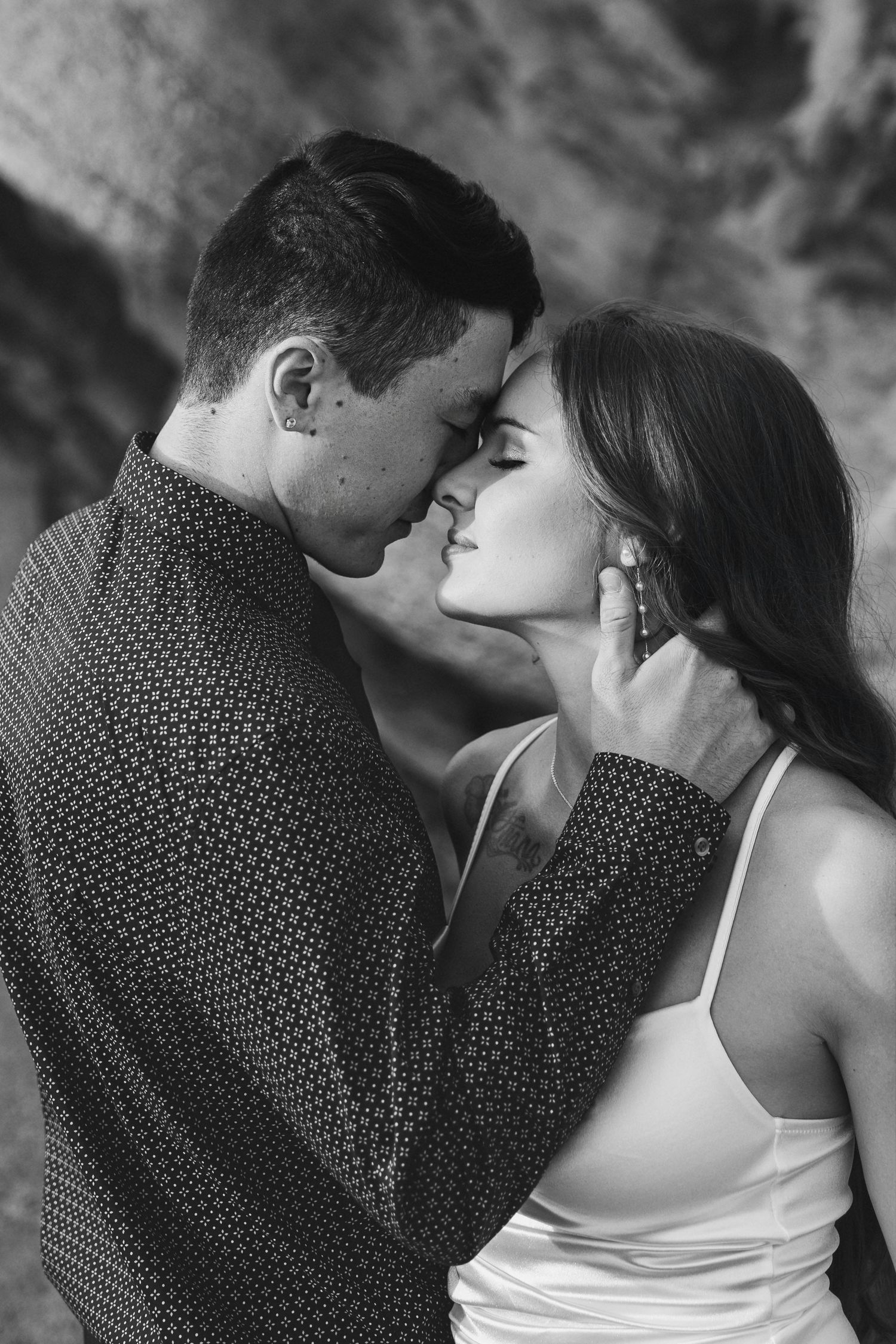 A romantic black and white portrait of a couple in an intimate embrace, with the man wearing a patterned shirt.