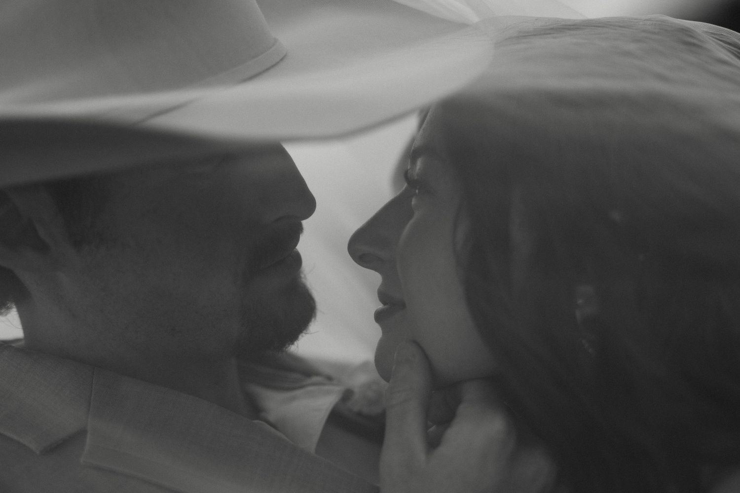 Intimate black and white portrait of bride and groom gazing at each other closely.