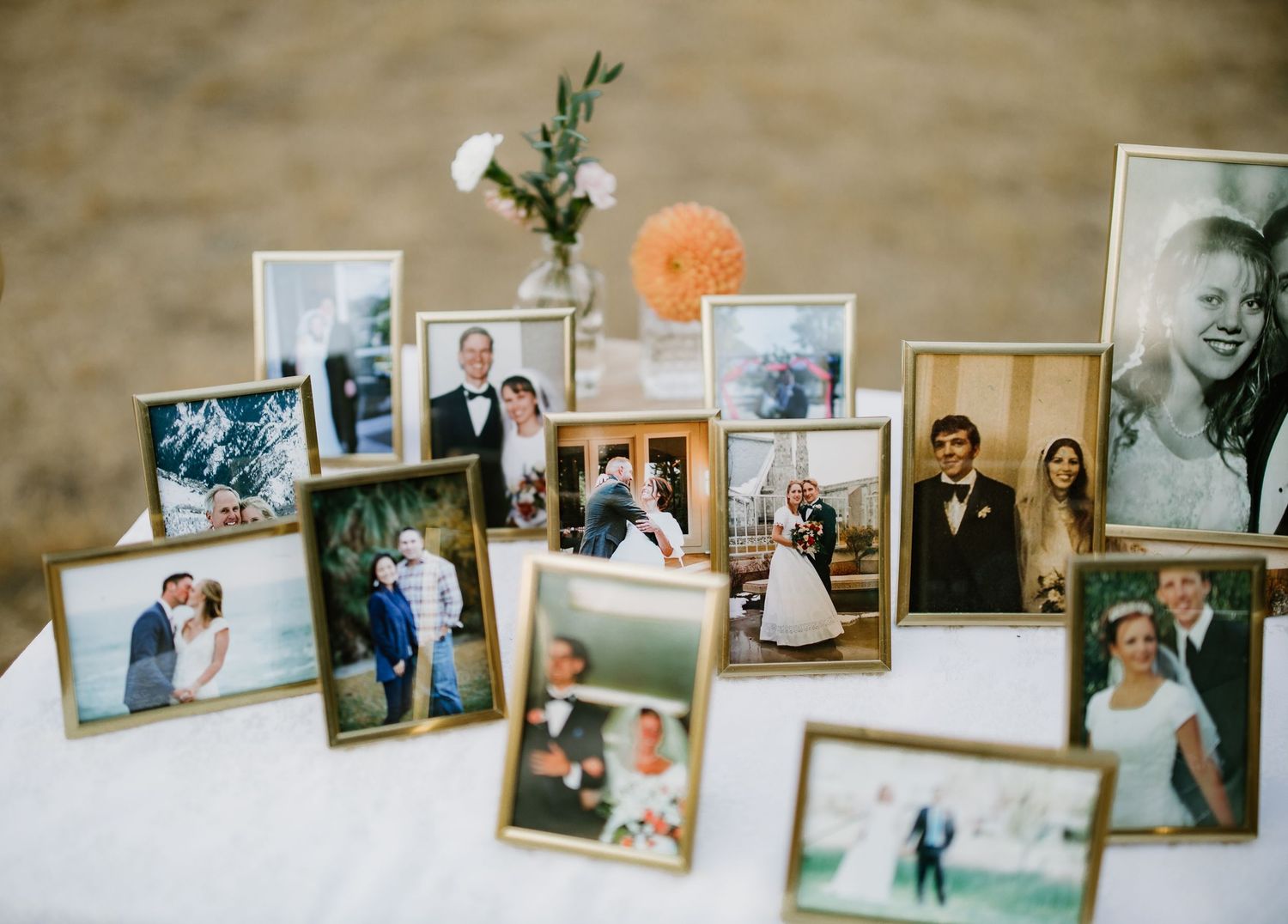 Collection of framed wedding photos displayed on a white table as decorative memory display at a wedding.