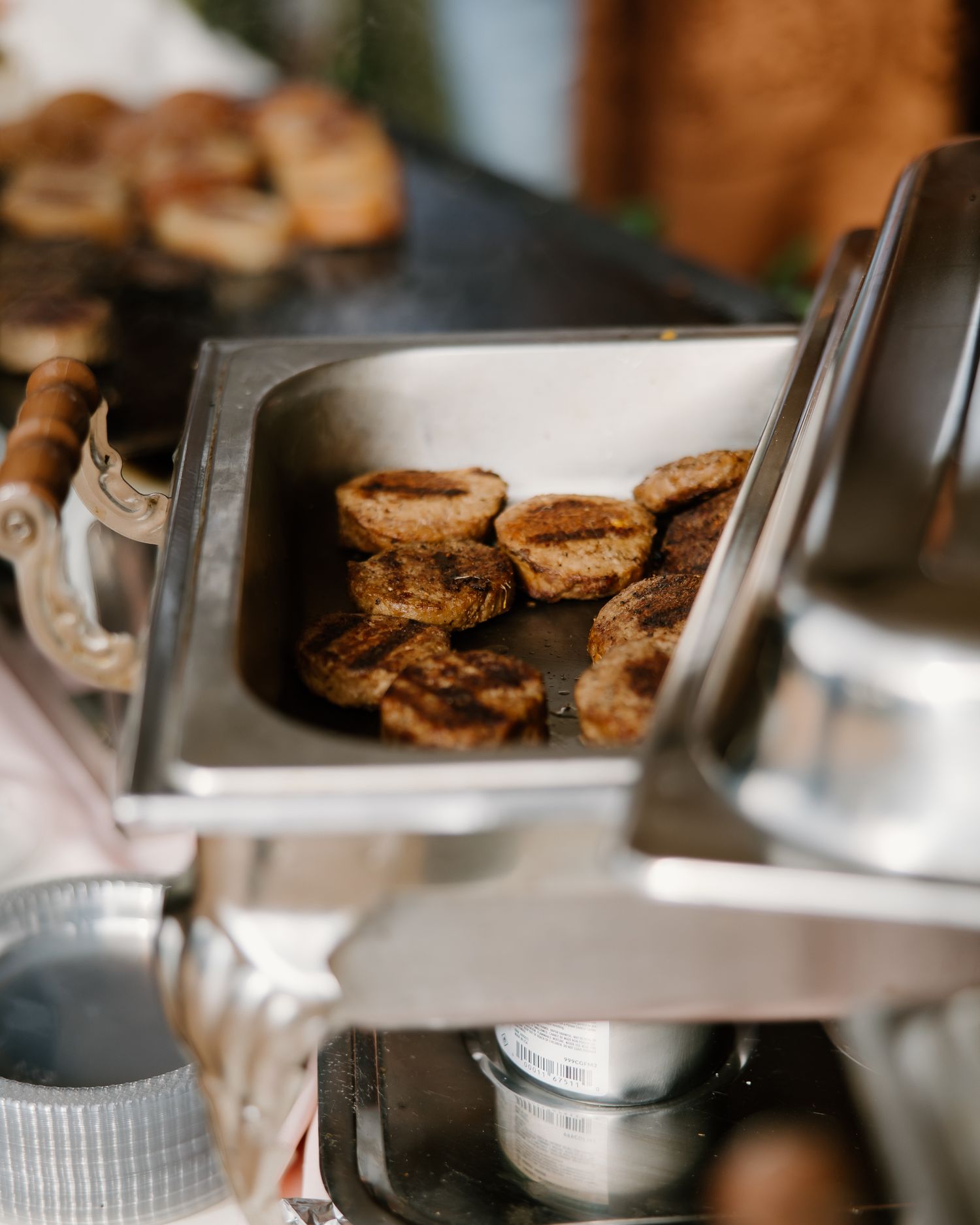 Savory grilled meat slices sizzling in a stainless steel chafing dish at a wedding catering station.