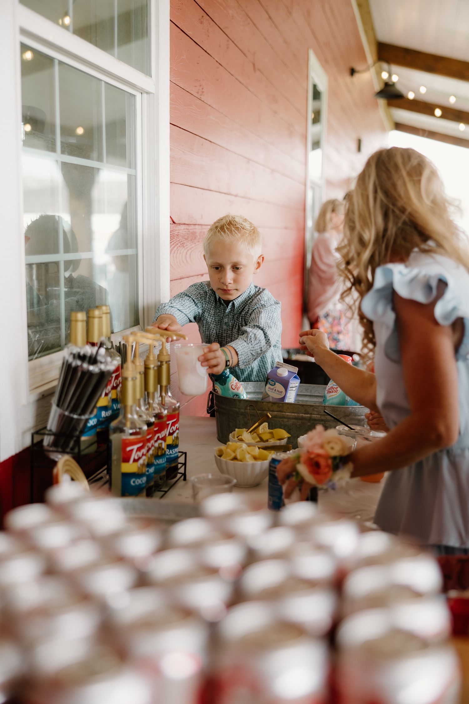 Young boy serves himself at a snack bar during a wedding reception at a rustic red barn venue.