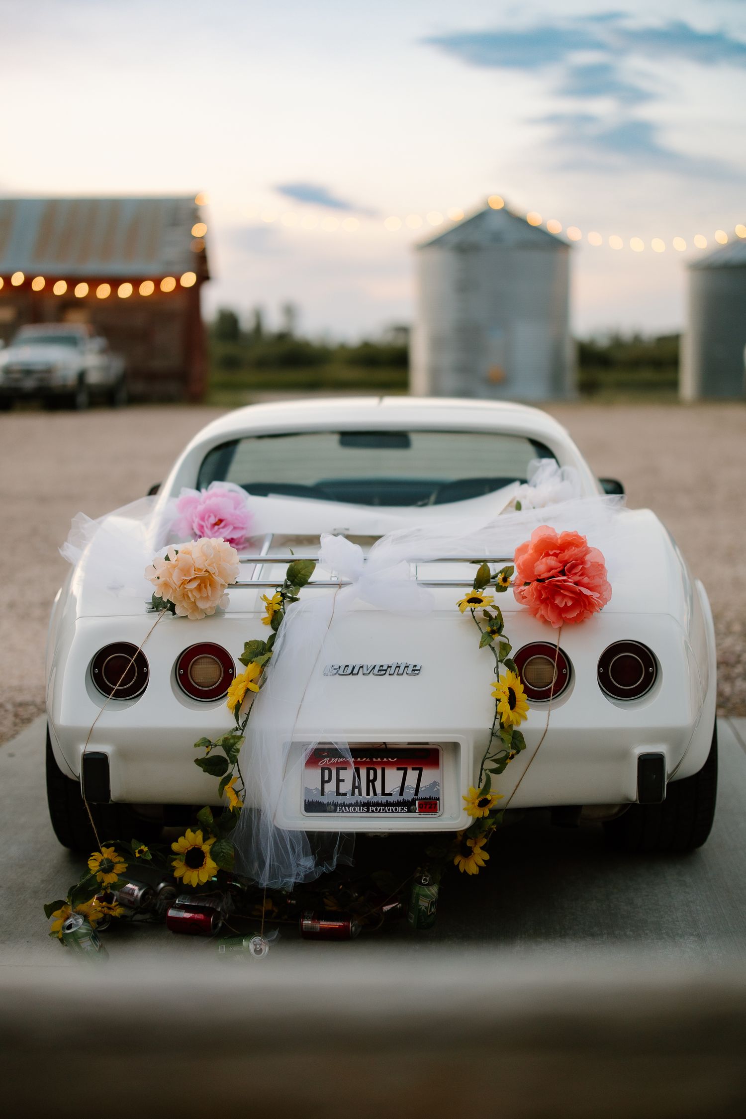 White vintage Corvette decorated with flowers and tulle with PEARL77 license plate at a wedding.