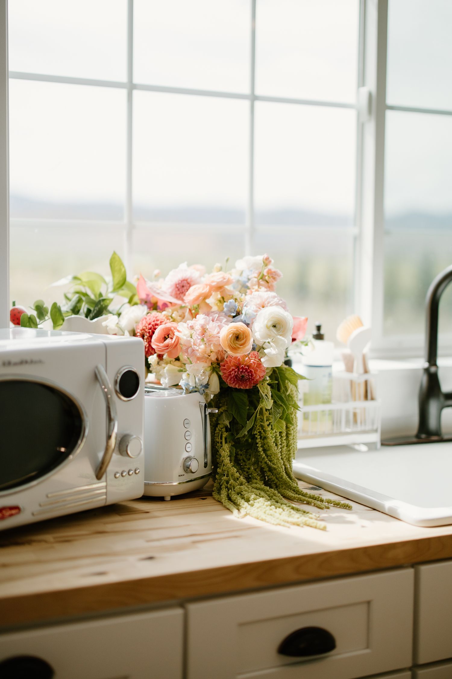 Bridal bouquet of pink and white flowers displayed on a wooden kitchen counter.