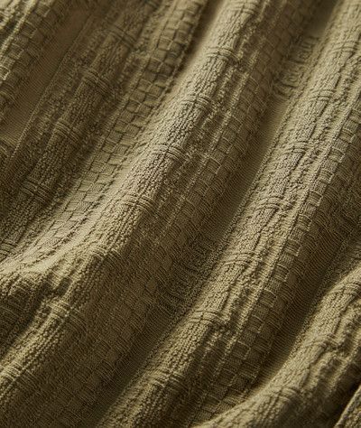 Close-up of textured olive green crinkled fabric with a subtle woven grid pattern.