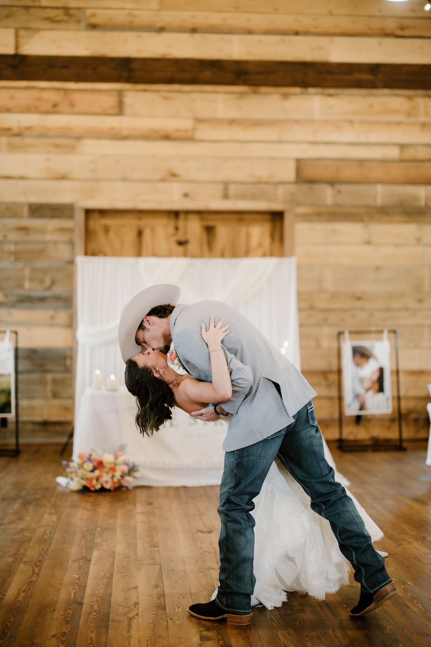 Groom dipping and kissing bride during first dance in a rustic wooden barn reception venue.